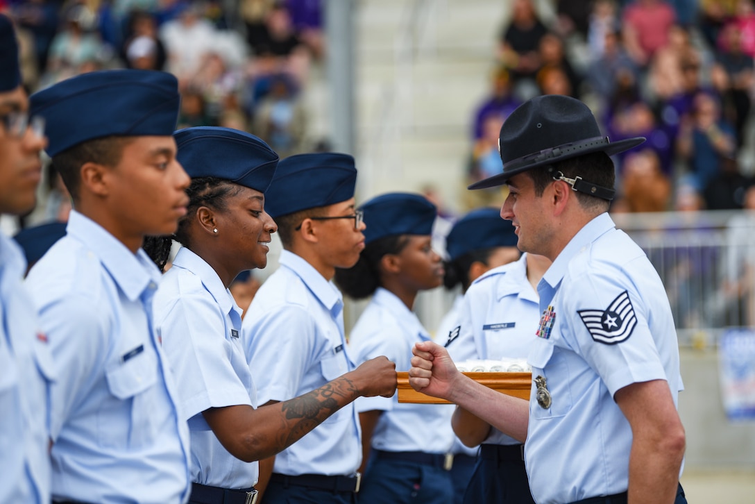 An airman fist bumps another in a line of airmen and guardians.