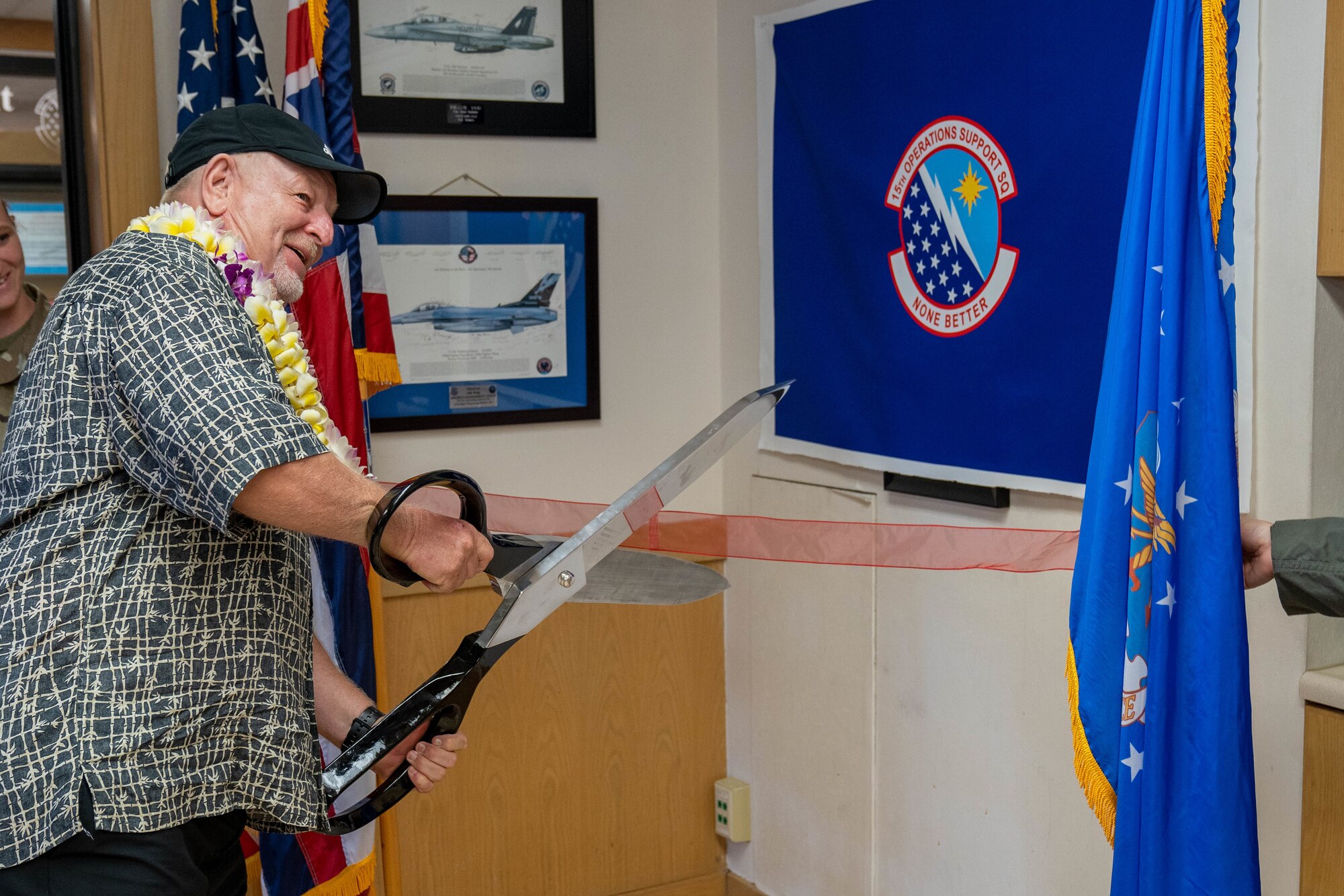 Retired Chief Master Sgt. Larry Smith prepares to cut the ribbon during a conference room renaming ceremony at Joint Base Pearl Harbor-Hickam, Hawaii, March 30, 2022. The conference room was renamed the Larry Smith Mission and Planning Room in honor of Smith’s 44 years of service in the Air Force and decades of support to the 15th Operations Group. (U.S. Air Force photo by Airman 1st Class Makensie Cooper)