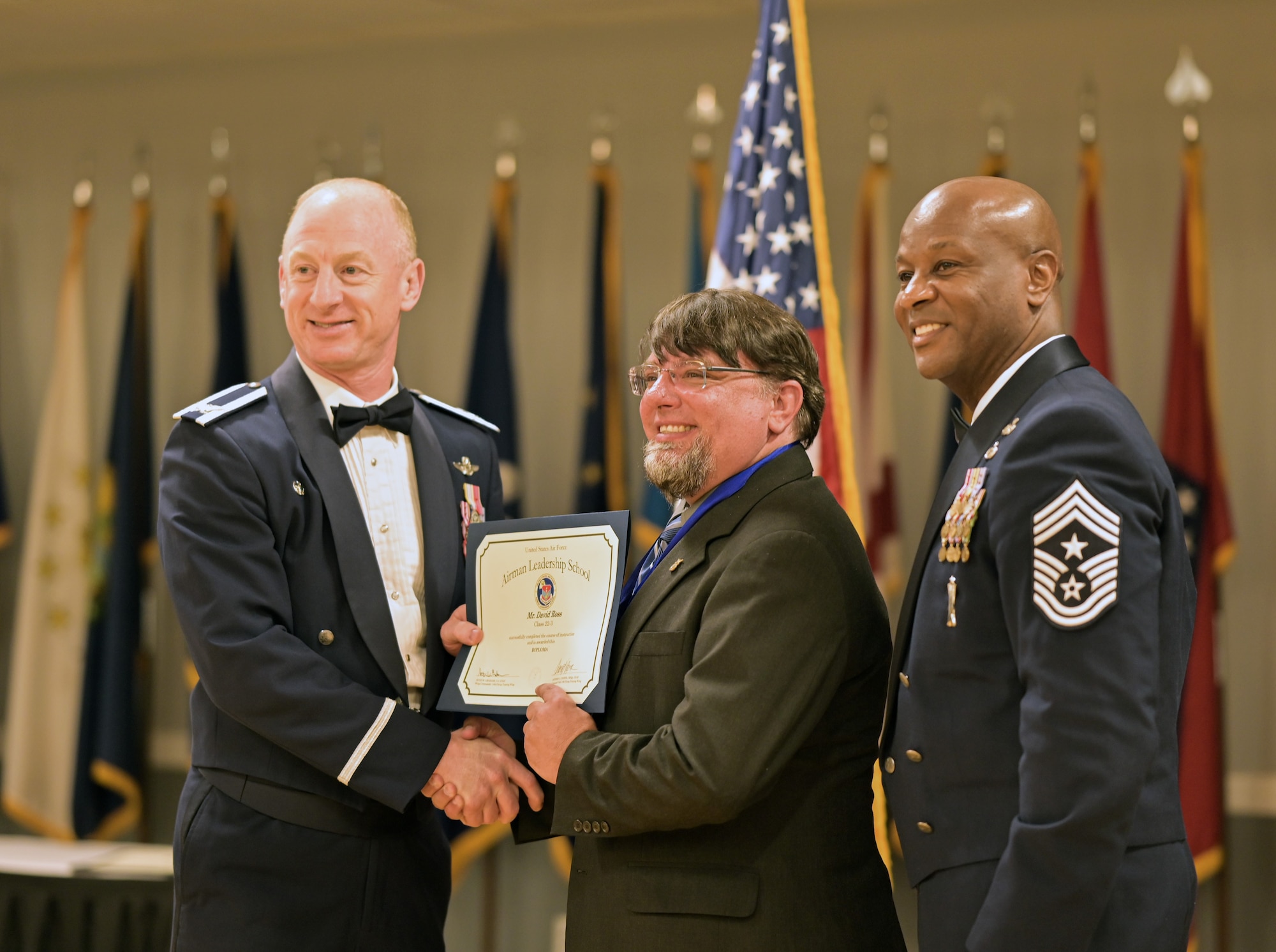 Col. Seth Graham, 14th Flying Training Wing commander, Chief Master Sgt. Antonio Cooper, 14th FTW command chief, pose for a photo with Mr. David Ross, 14th Medical Group optometry technician, at the Airman Leadership School graduation ceremony on March 31, 2022, at Columbus Air Force Base, Miss. Ross was the first civilian graduate from ALS. (U.S. Air Force photo by Senior Airman Davis Donaldson)