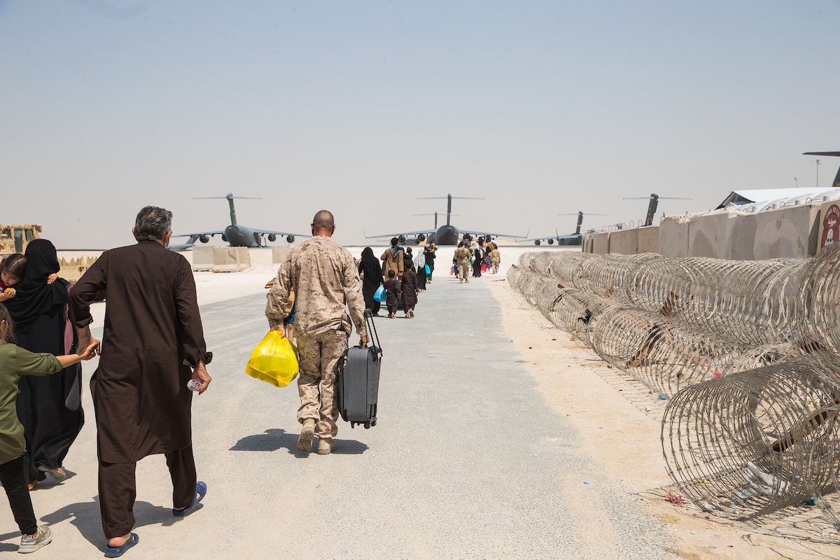 People, including U.S. service members, walk toward several aircraft.