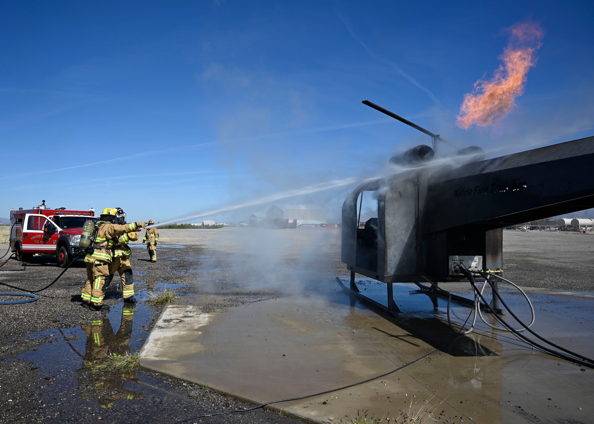 Senior Airman Daniel Portillo, a firefighter with the 162nd Civil Engineer Squadron, directs his commander, Lt. Col. Paul Boriack, where to aim the hose to extinguish a fire while training at Davis-Monthan Air Force Base, Arizona. Guardsmen from the 162nd Wing partner with firefighters at D-M every year to conduct realistic and dynaimc training at the active duty base's robust facilities. (U.S. Air National Guard photo by Maj. Mary Hook)
