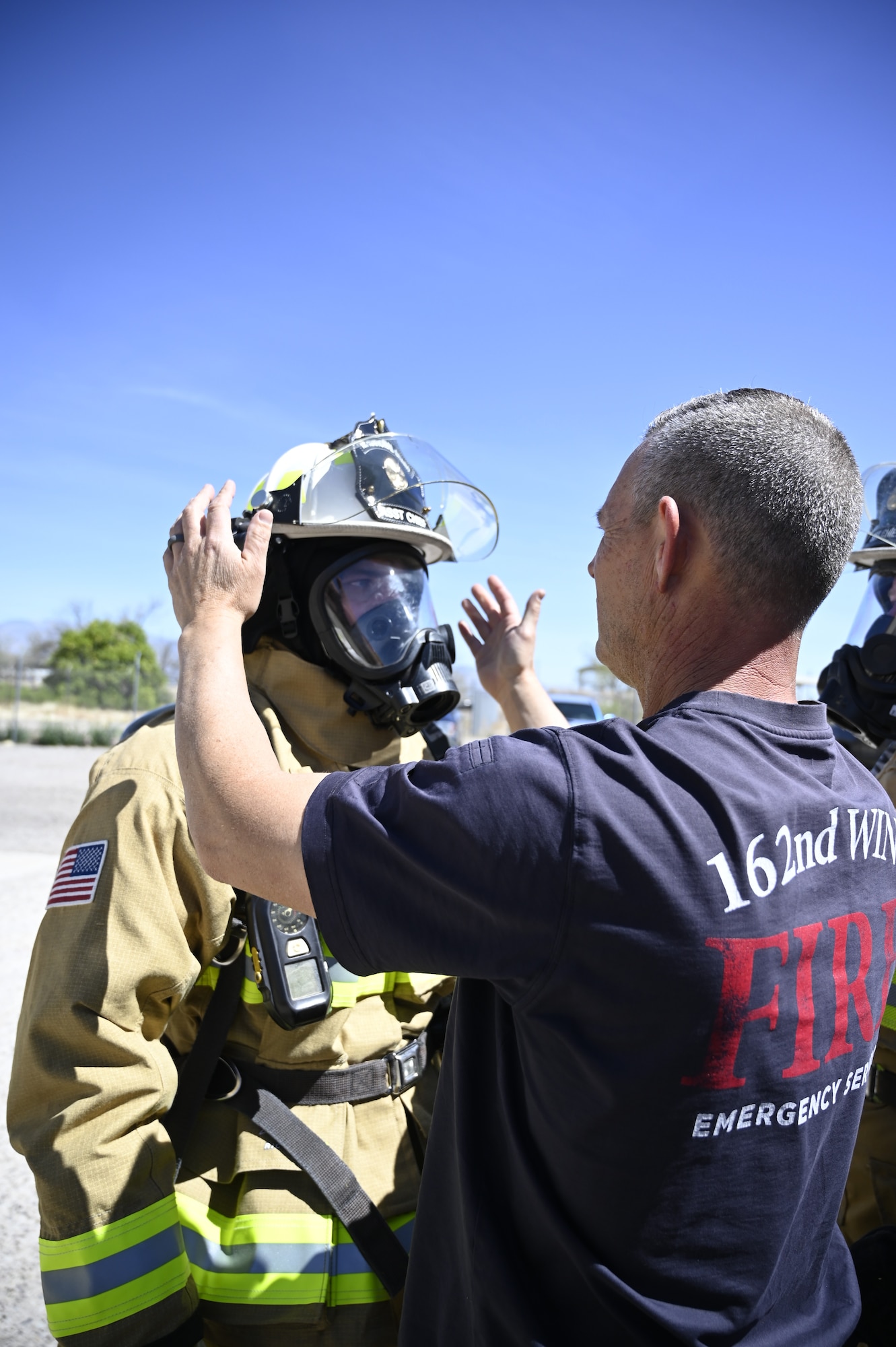 Joe Linehan, a firefighter with the 162nd Civil Engineer Squadron, helps his commander, Lt. Col. Paul Boriack, adjust his gear in preparation for live-fire training at Davis-Monthan Air Force Base, Arizona. Guardsmen from the 162nd Wing partner with firefighters at D-M every year to conduct realistic and dynaimc training at the active duty base's robust facilities. (U.S. Air National Guard photo by Maj. Mary Hook)