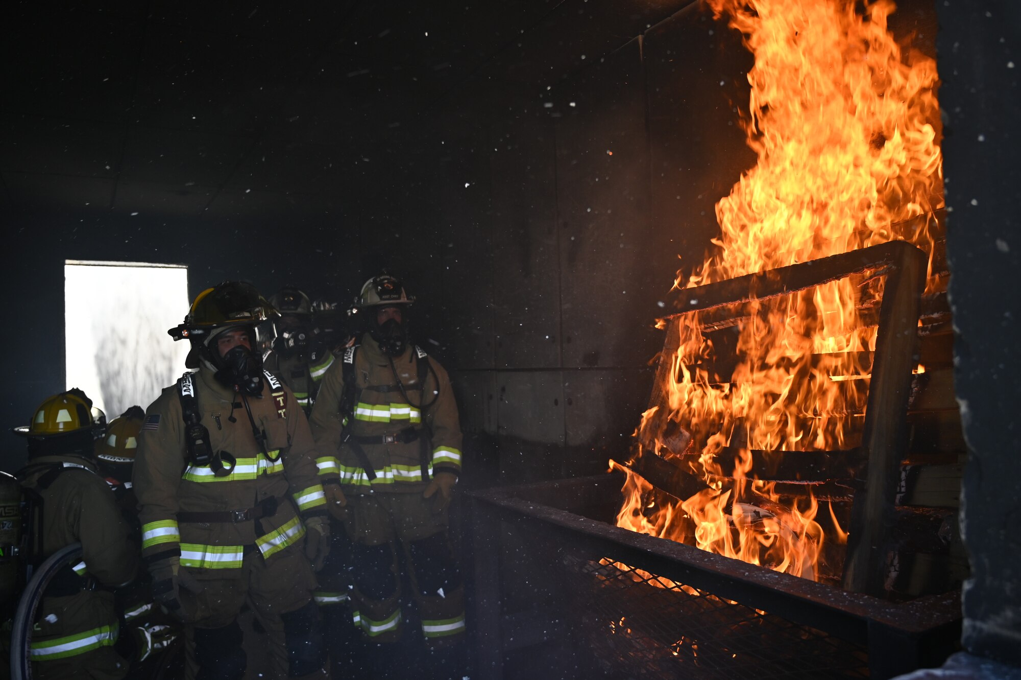 Firefighters from the 162nd Wing observe the dynamics of a fire as fellow fighters perform a hydraulic ventilation in the live-fire house at Davis-Monthan Air Force Base, Arizona. Guardsmen from the 162nd Wing partner with firefighters at D-M every year to conduct realistic and dynaimc training at the active duty base's robust facilities. (U.S. Air National Guard photo by Maj. Mary Hook)