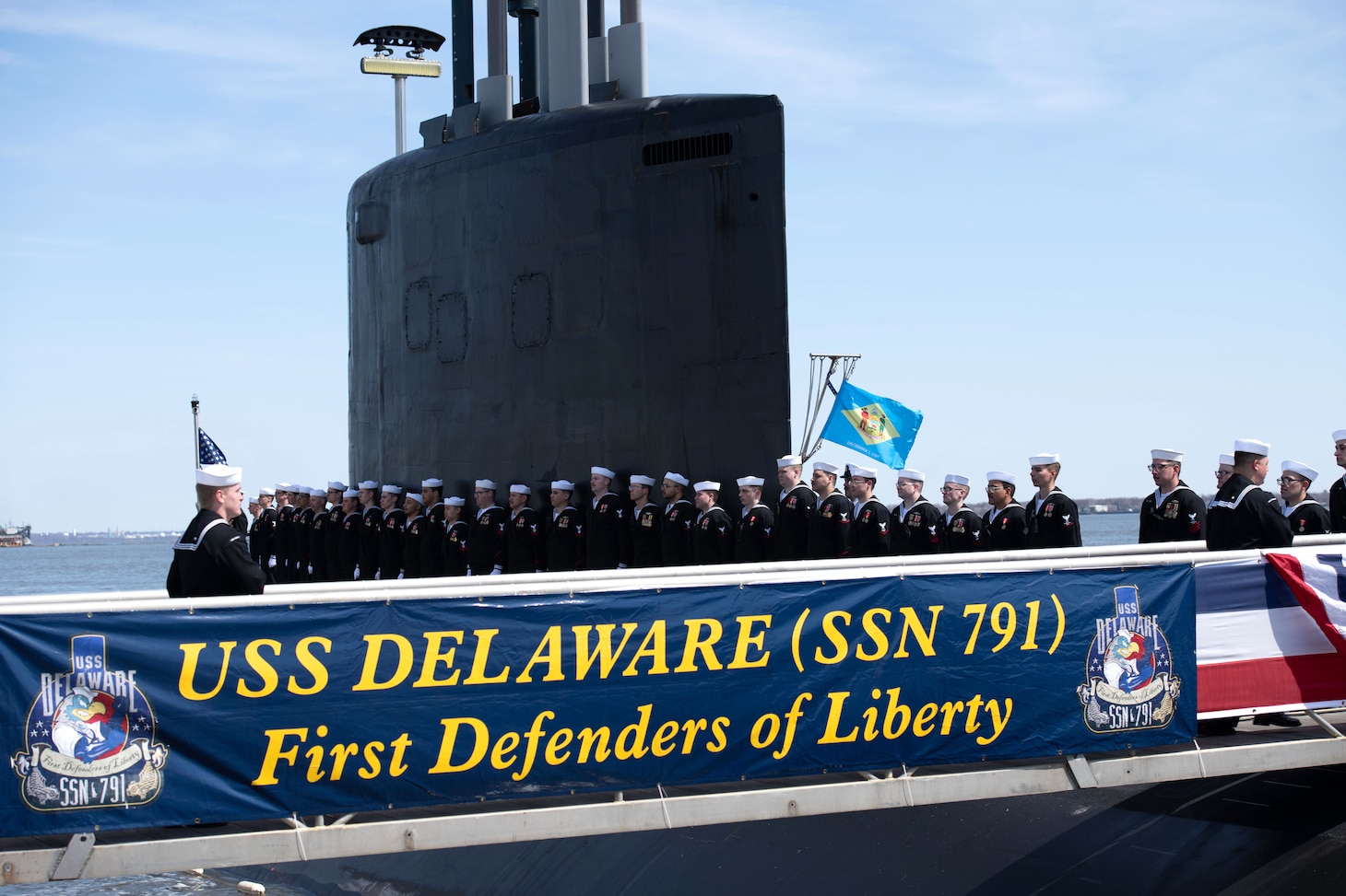 The crew of the Virginia-class submarine USS Delaware (SSN 791) board the ship during a commissioning commemoration ceremony in Wilmington, Delaware April 2, 2022.