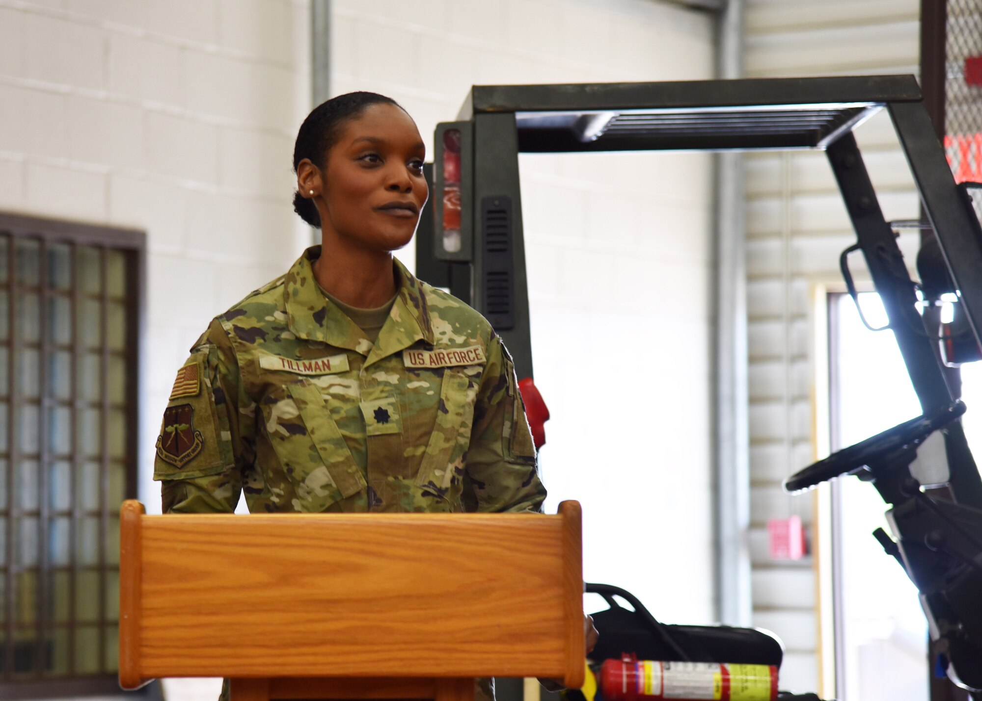 Lt. Col. Tillman stands behind a podium and looks out in front of her