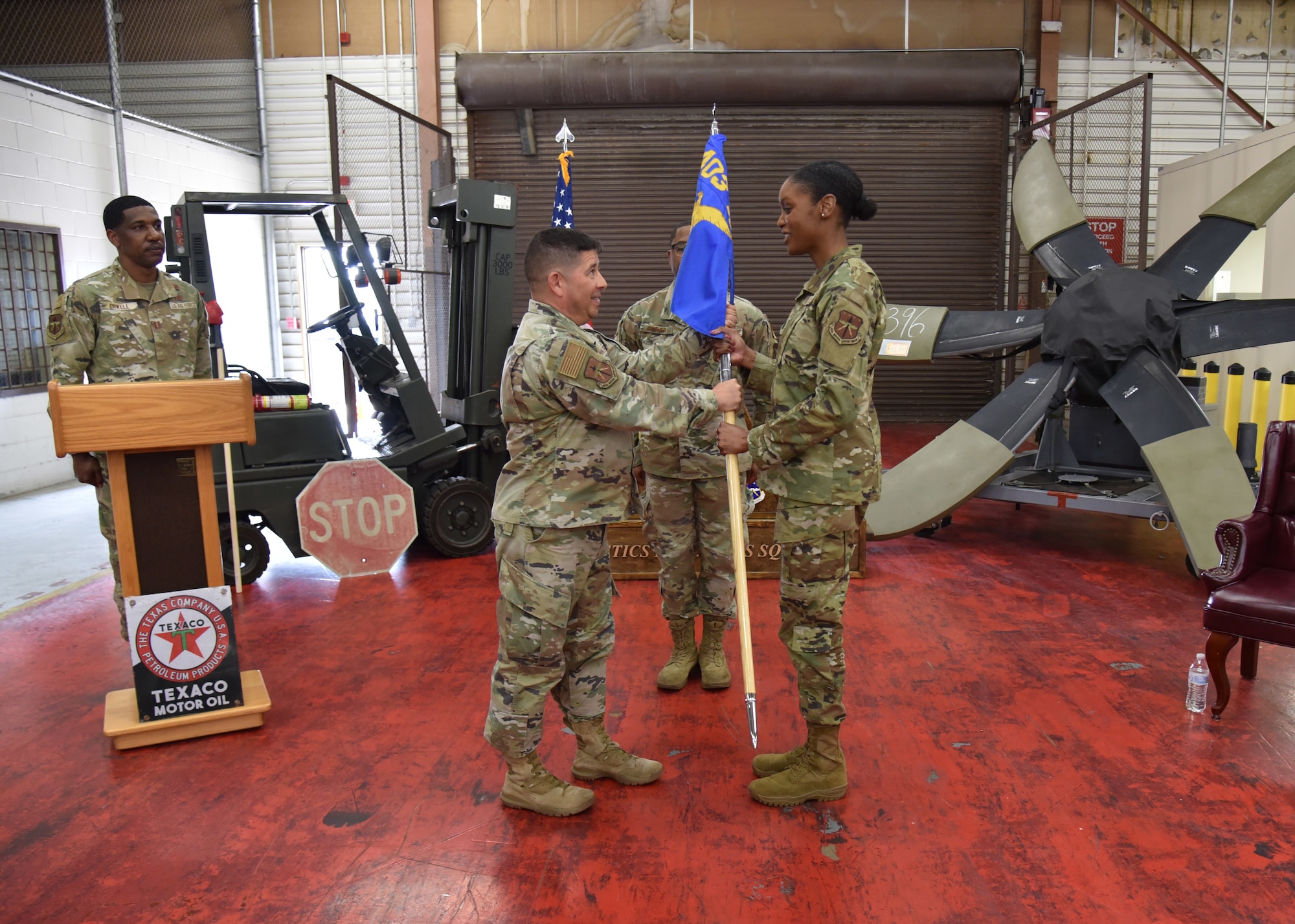 Col. Trujillo hands a guidon to Lt. Col Tillman as the guidon bearer stands behind them.