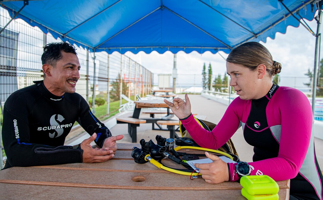 U.S. Marine Corps Cpl. Madeline Prine, right, an automotive maintenance technician with 7th Communication Battalion, III Marine Expeditionary Force Information Group, reviews scuba diving techniques with Sgt. Dennis Ruiz, left, an infantry assault Marine with 2nd Battalion, 7th Marine Regiment, 1st Marine Division, on Camp Schwab, Okinawa, Japan, March 24, 2022. Prine is a certified scuba instructor through the Professional Association of Diving Instructors. (U.S. Marine Corps photo by Cpl. Alex Fairchild)