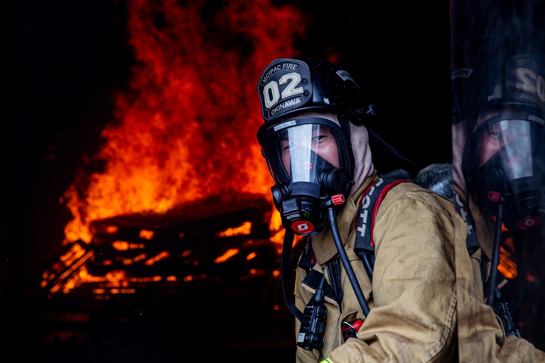 A firefighter with Marine Corps Installations Pacific Fire and Emergency Services observes a burning room during a bilateral live-fire training exercise on Camp Hansen, Okinawa, Japan, March 25, 2022. MCIPAC F&ES and the Naha City Fire Department assembled and conducted live-fire training to compare the different firefighting techniques and methods each department uses to accomplish the same mission. (U.S. Marine Corps photo by Cpl. Alex Fairchild)

