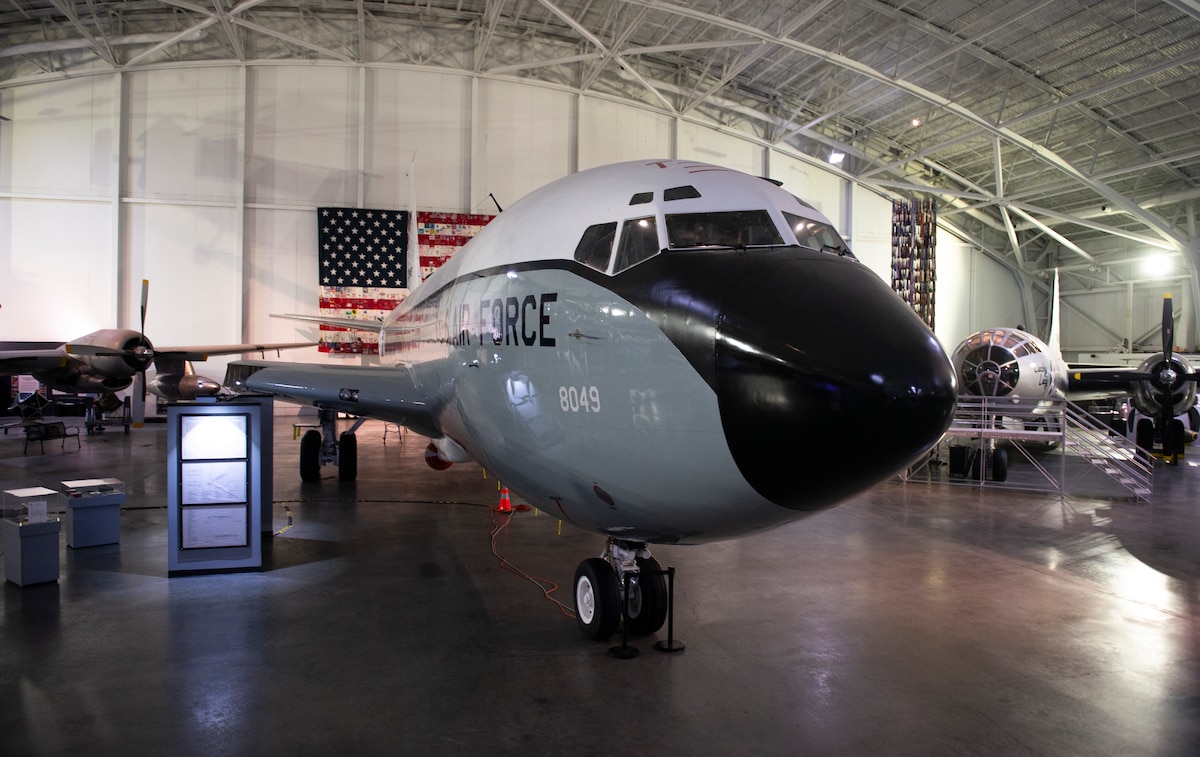 An EC-135C Looking Glass aircraft with its wings removed sits in a hangar