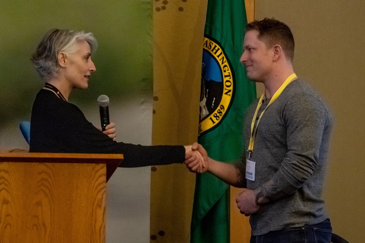 Photo of Chief Master Sgt. Vickie Robertson, Air Reserve Personnel Center command chief master sergeant, provide a recognition coin to Tech. Sgt. Zachary Nicholas, 419th Force Support Squadron, at a Yellow Ribbon event in Bellevue, Washington, March 20, 2022.