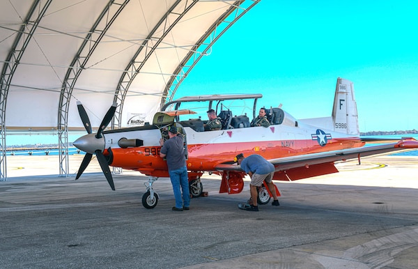 Fleet Readiness Center Southeast (FRCSE) pilots, Lt. Cmdr. Joseph Breeden and Lt. Cmdr. Andrew Konowicz, finish parking a Navy T-6A under an Environmental Protection Shelter after completing a post-aircraft condition inspection functional check flight. The shelters are the first aboard Naval Air Station Jacksonville and were designed to withstand 135 mph winds and protect aircraft and personnel from the harsh Florida weather.