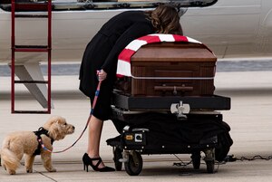 Lauren Tomkiewicz grieves at the casket of her husband Capt. Matthew Tomkiewicz upon his arrival at the 122nd Fighter Wing ANG base Indiana. The couple’s dog, Kevin Bacon, is by her side. Tomkiewicz and three others died during a training mission March 18, near Bodo Norway. The Marines were participating in Exercise Cold Response 2022. (U.S. Air Force photo/Douglas Hays)