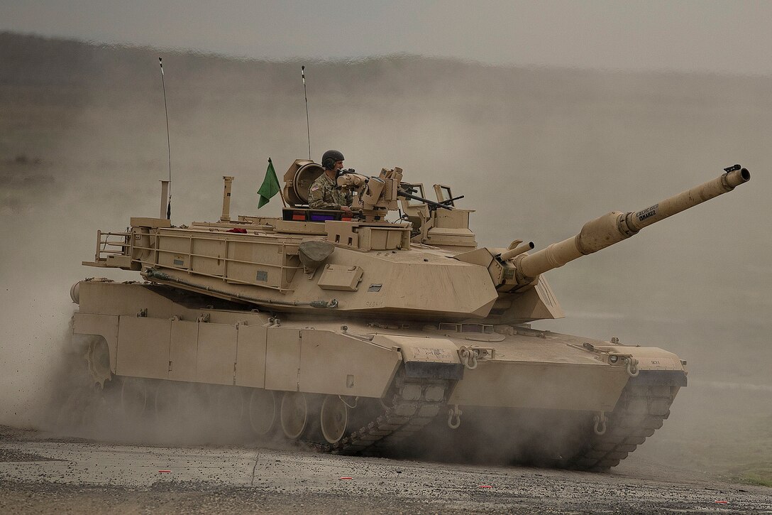 A soldier operates a tank in a field.