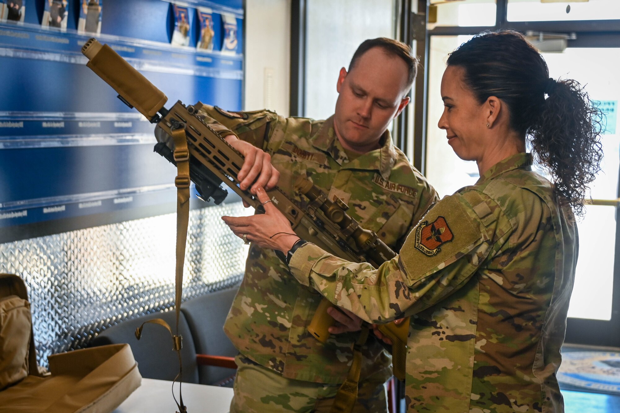 U.S. Air Force Chief Master Sgt. Kristina Rogers, 19th Air Force command chief, takes an M110-A1 advanced marksman rifle from Staff Sgt. Chance Dority, 97th Security Forces Squadron (SFS) combat arms assistance noncommissioned officer in charge, at Altus Air Force Base, Oklahoma, March 31, 2022. The 97th SFS Airmen briefed Rogers on several new items and events, such as the M110-A1 and the standard training they go through. (U.S. Air Force photo by Senior Airman Kayla Christenson)