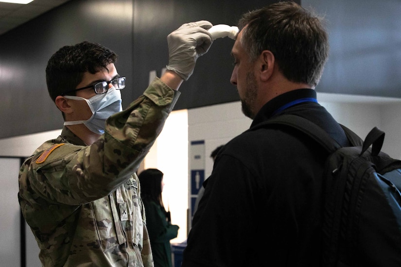 A civilian’s temperature is taken for potential COVID-19 exposure.