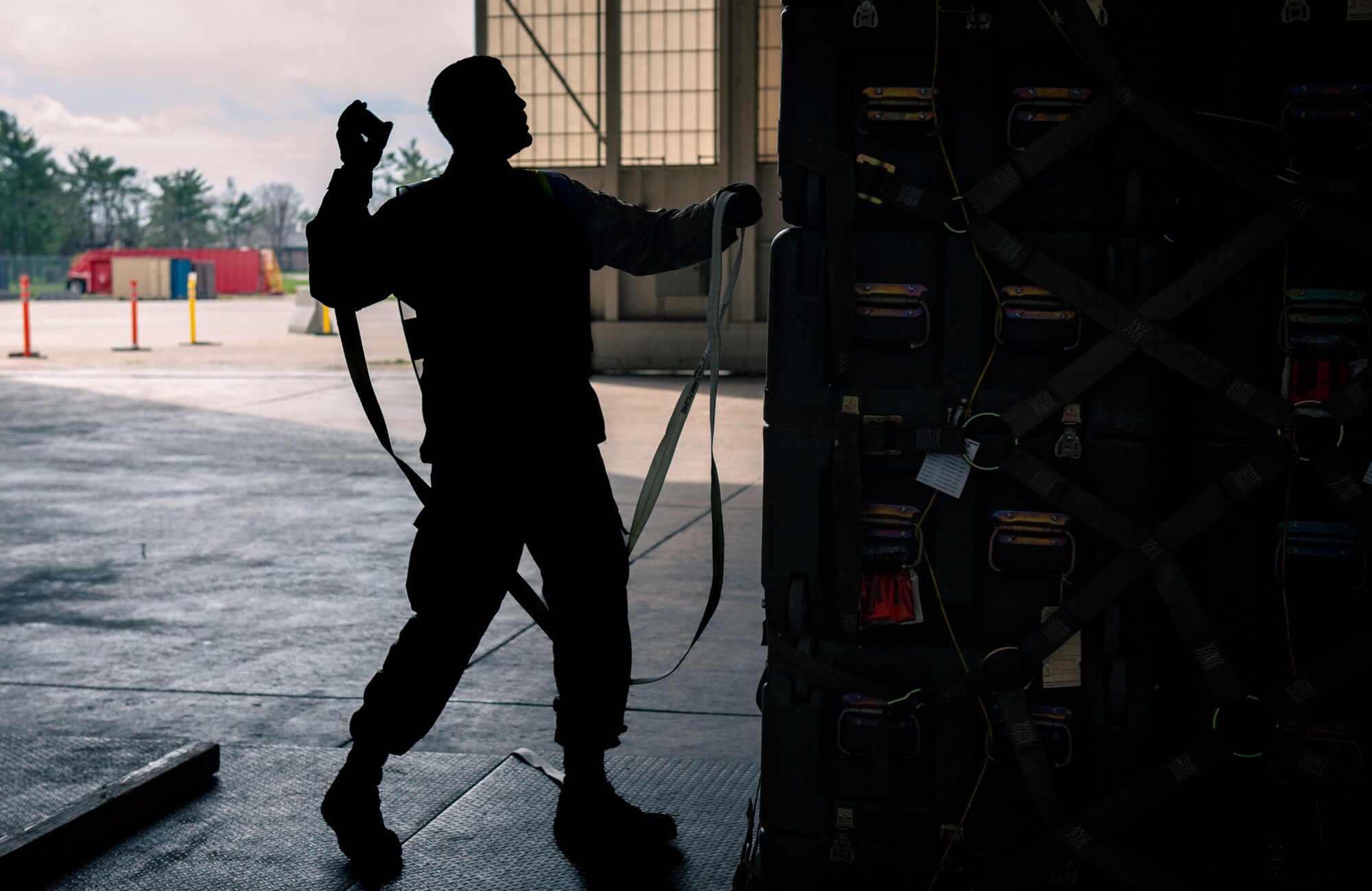 Senior Airman Jesus Lopez-Rios, an aerial porter for the 305th Aerial Port Squadron, throws a net fastener over a cargo pallet during Readiness Exercise 2022 on Joint Base McGuire-Dix-Lakehurst, April 1, 2022. Readiness exercises demonstrate Air Mobility wings are ready to provide operationally ready, deliberately developed and professionally led Airmen to deploy and support operations in contested environments.