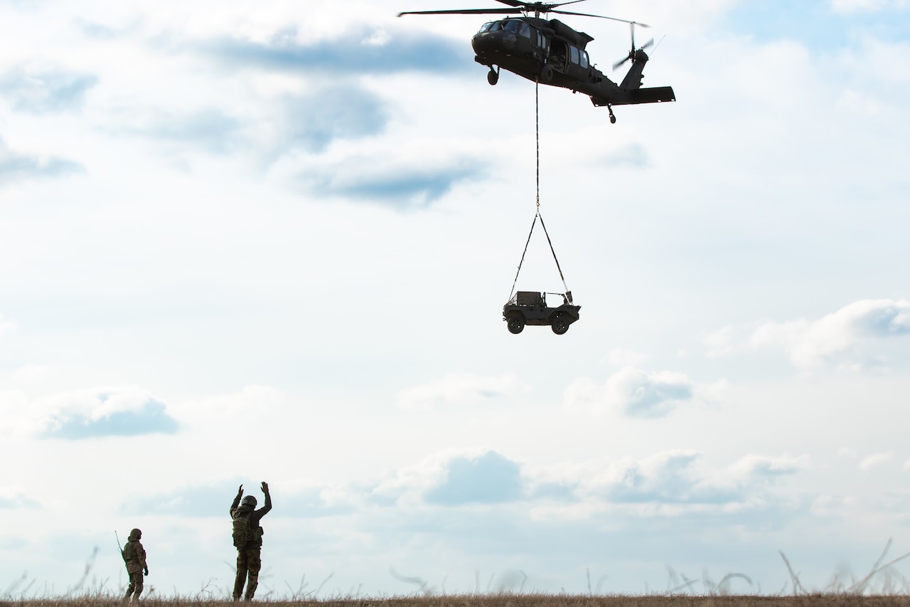 Soldiers on the ground look up at a helicopter.