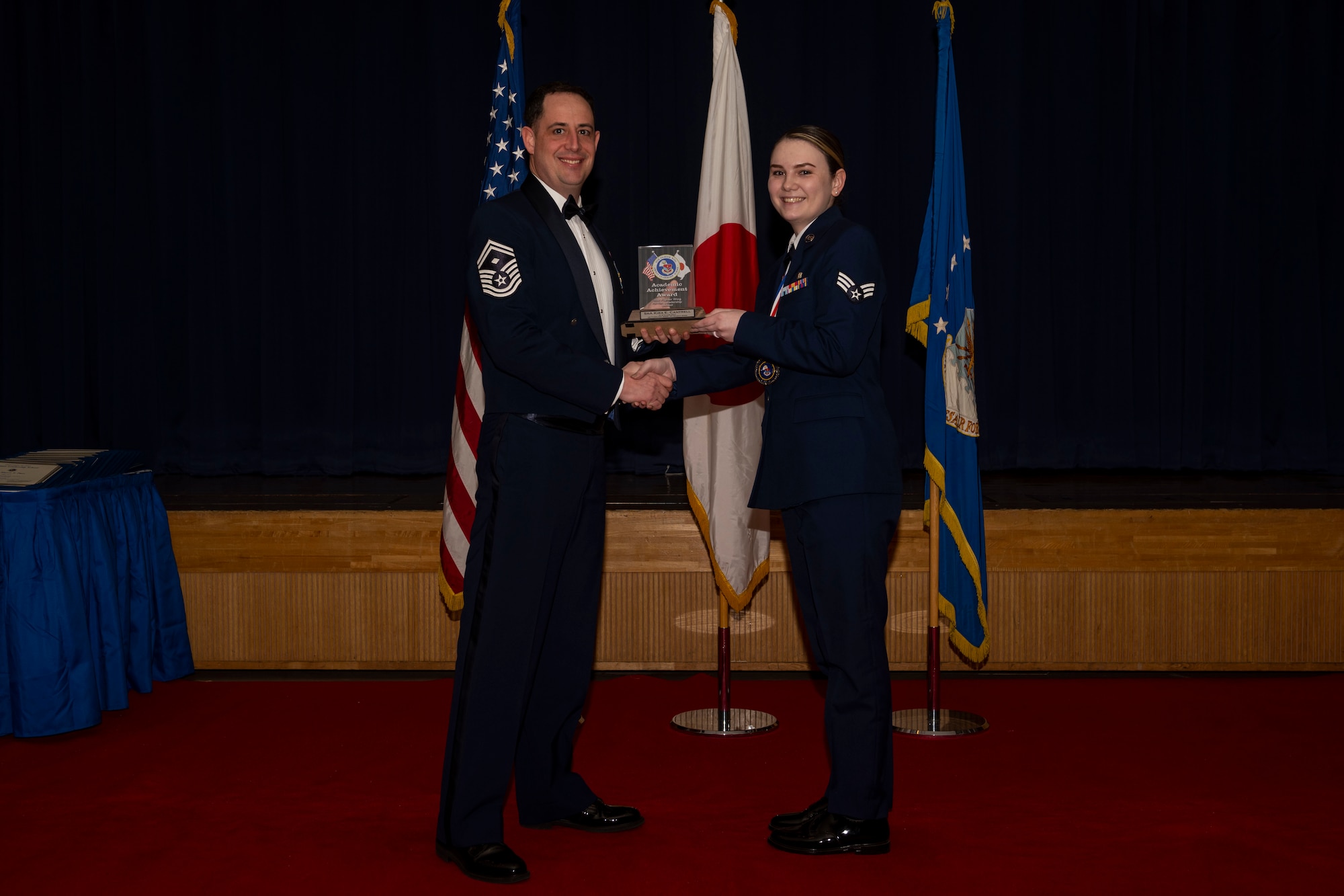 Group of military members in uniform pose for a photo holding an award.