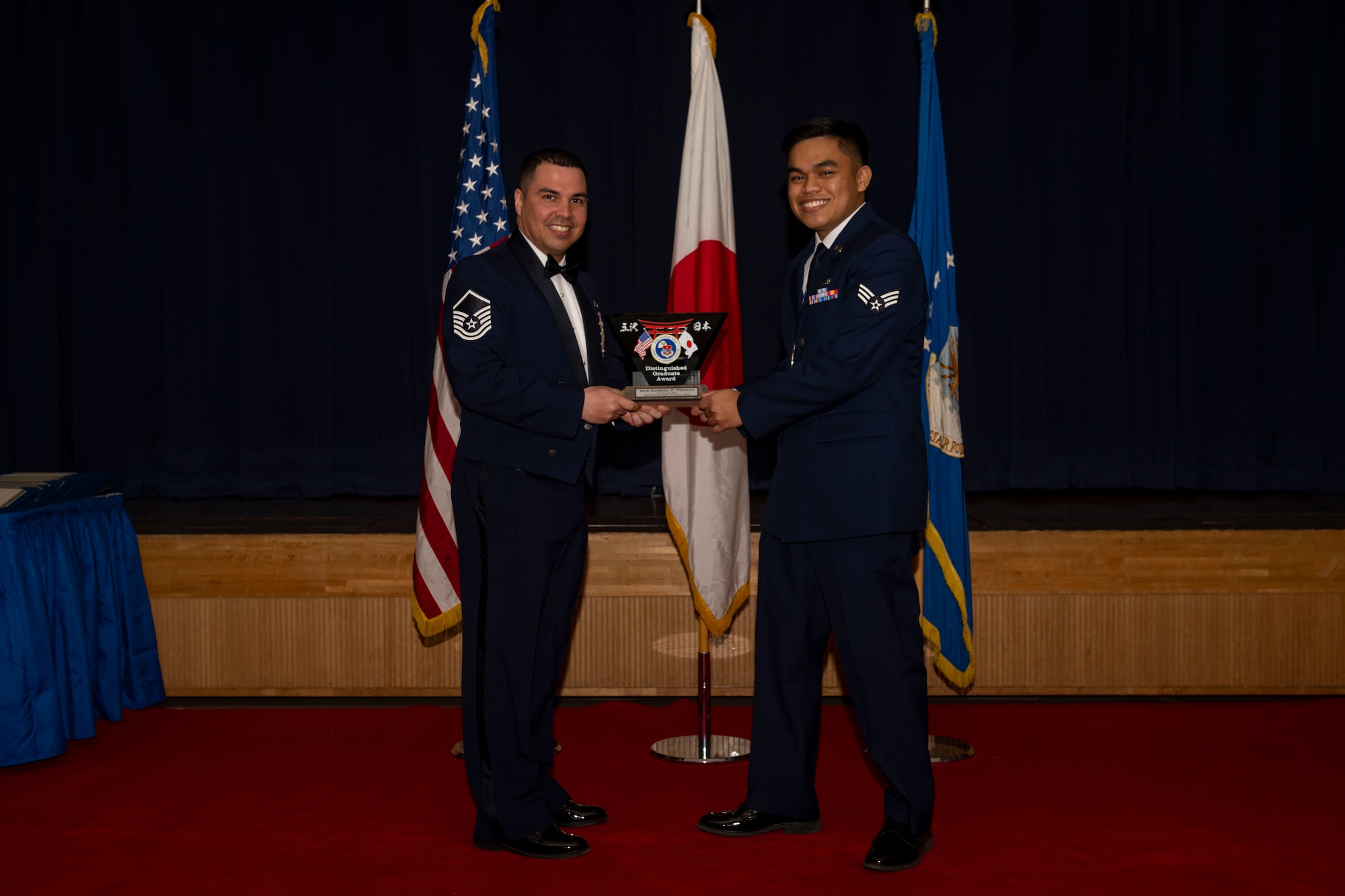 Group of military members in uniform pose for a photo holding an award.