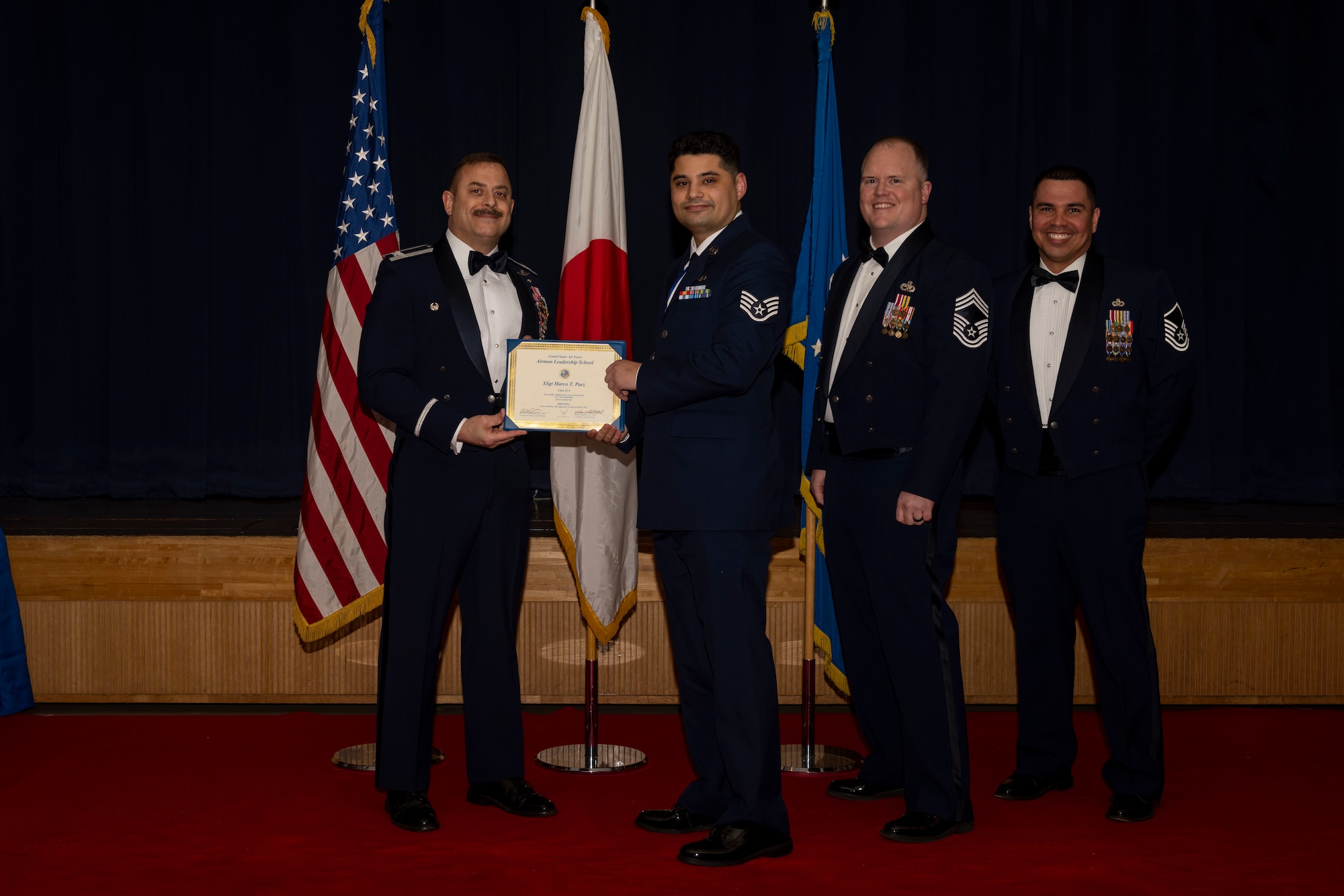 Group of military members in uniform pose for a photo holding a certificate.