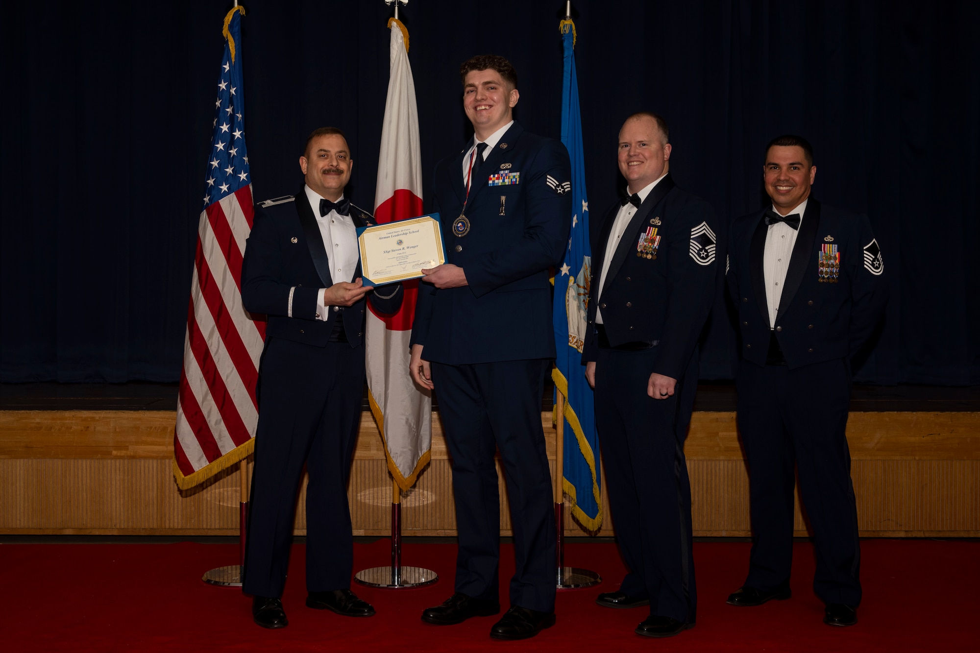 Group of military members in uniform pose for a photo holding a certificate.