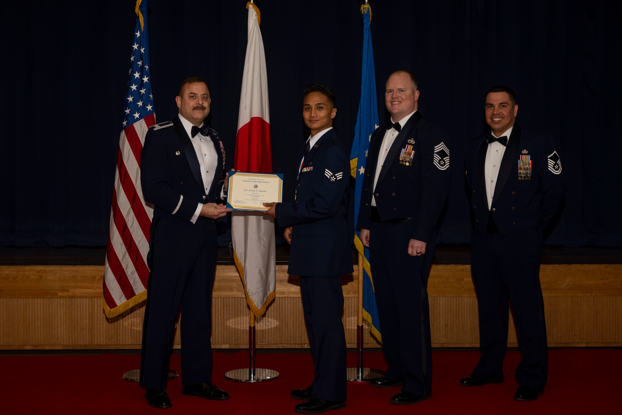Group of military members in uniform pose for a photo holding a certificate.