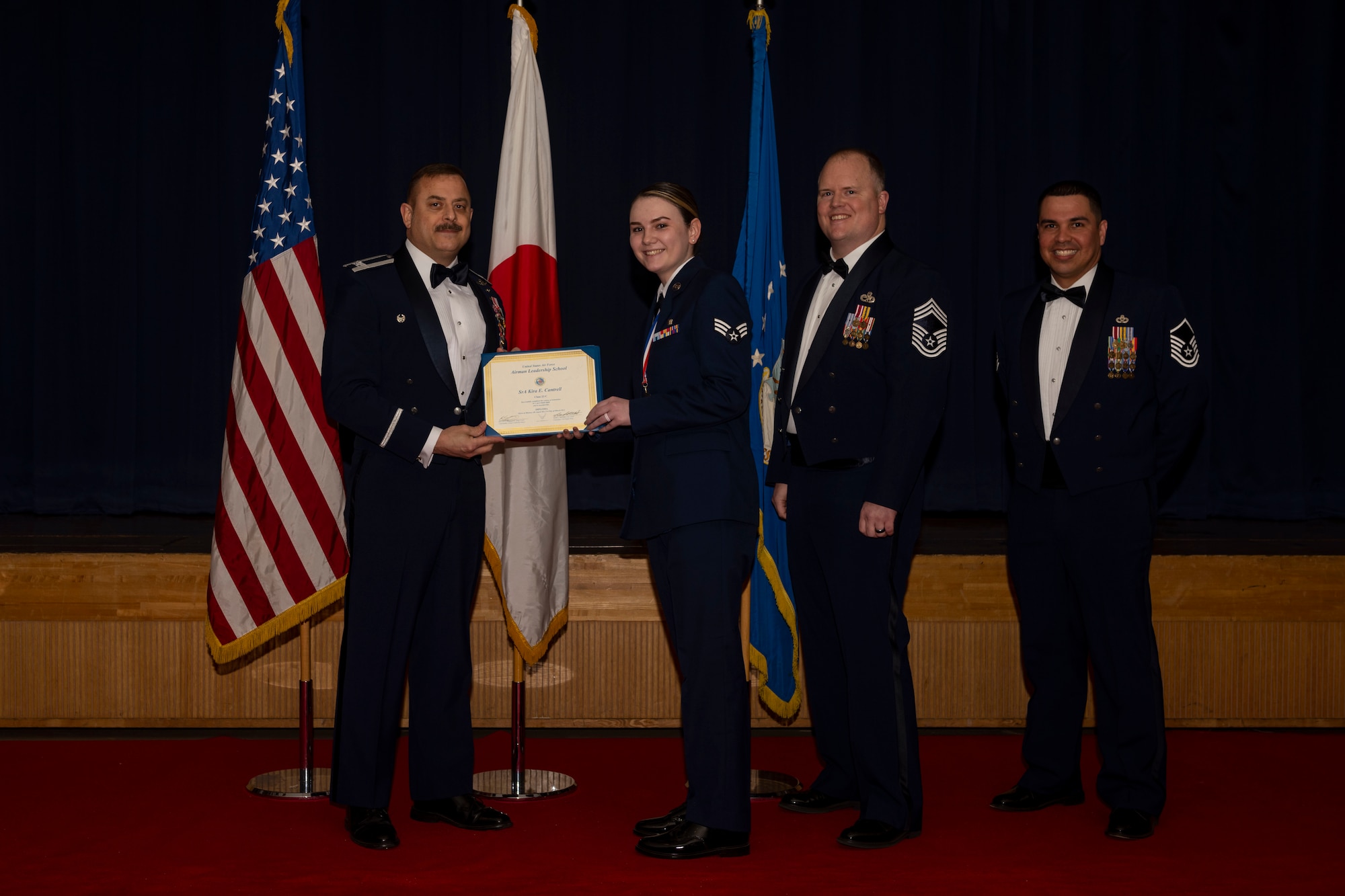 Group of military members in uniform pose for a photo holding a certificate.