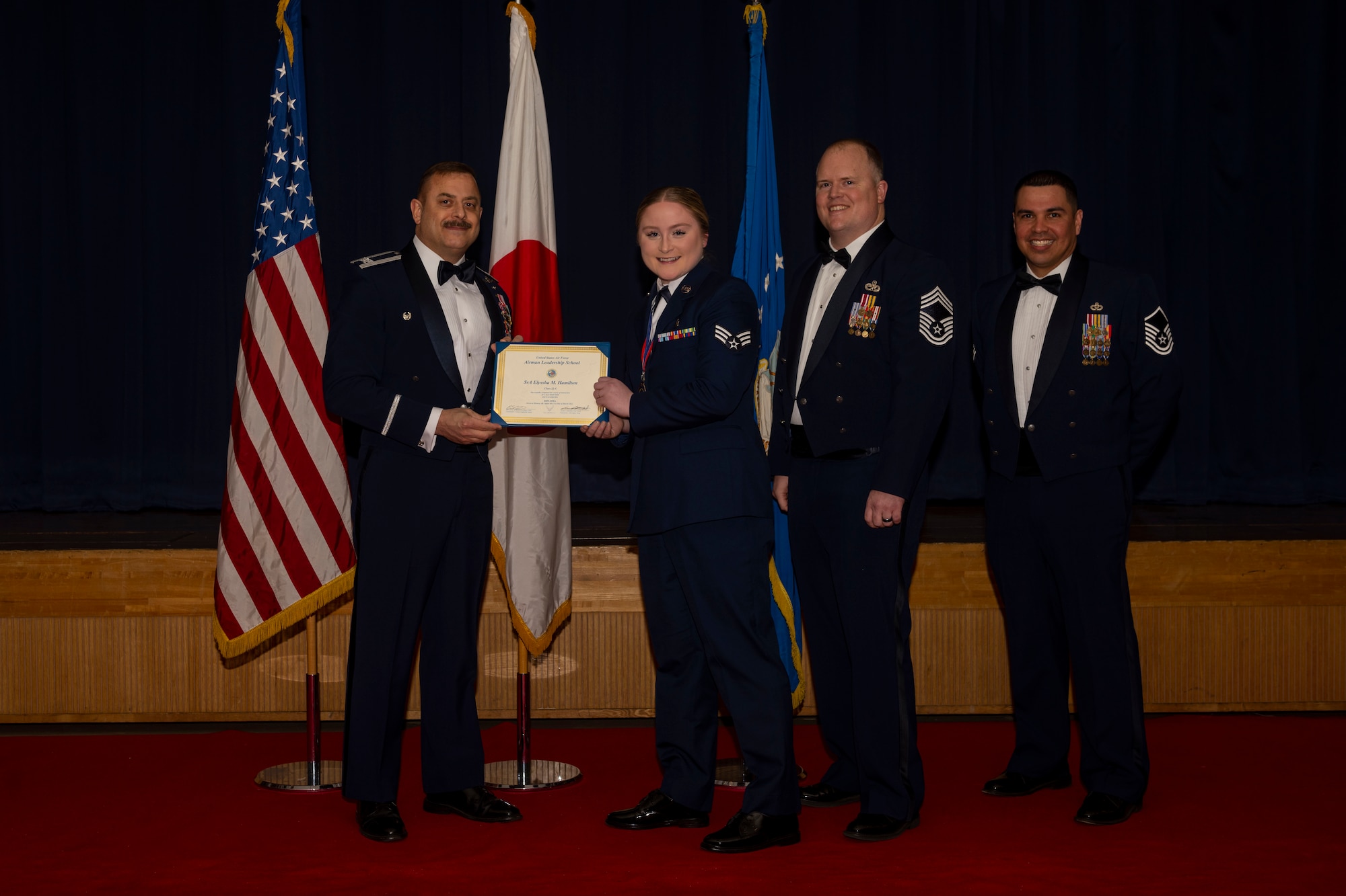 Group of military members in uniform pose for a photo holding a certificate.