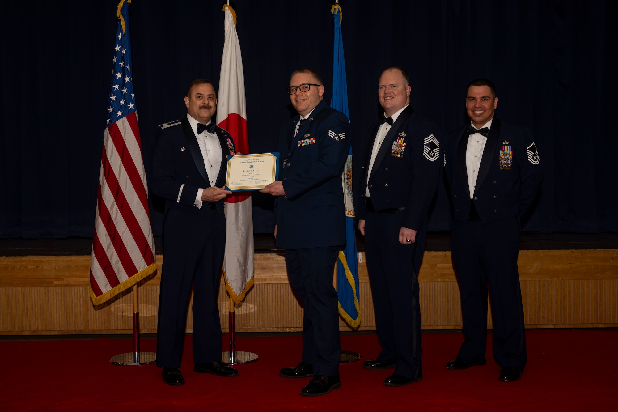 Group of military members in uniform pose for a photo holding a certificate.