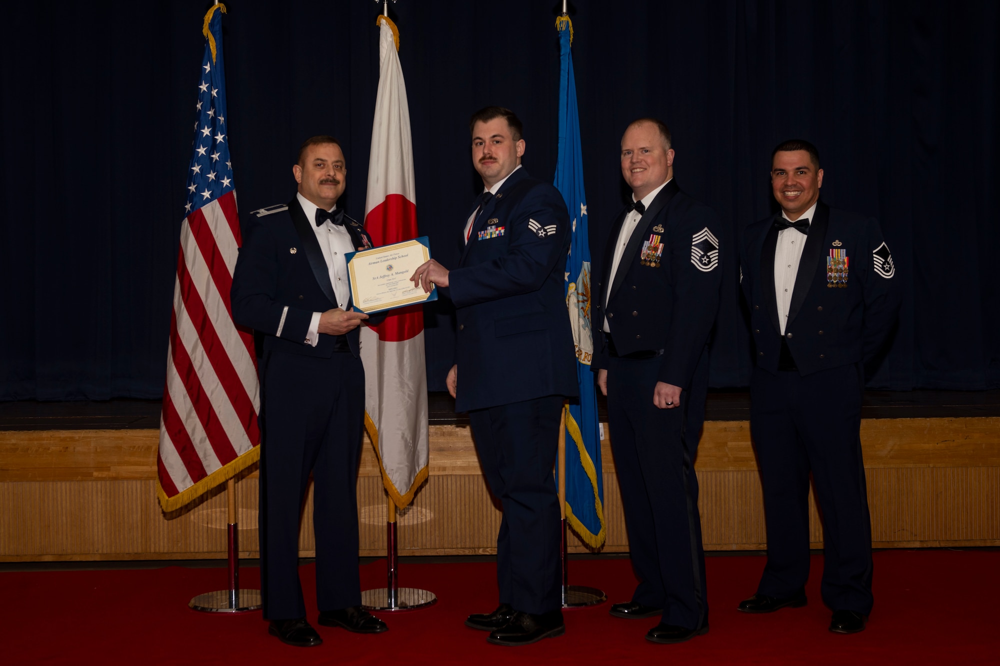 Group of military members in uniform pose for a photo holding a certificate.