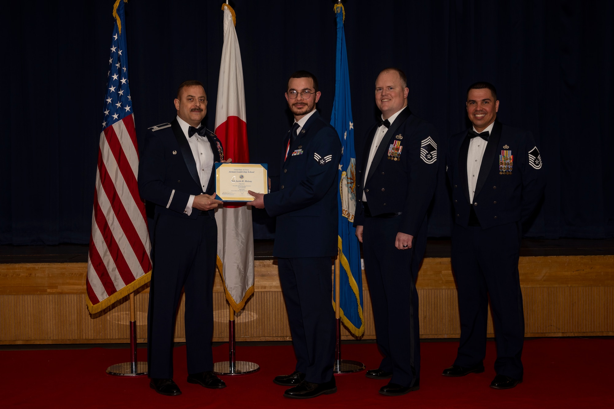 Group of military members in uniform pose for a photo holding a certificate.