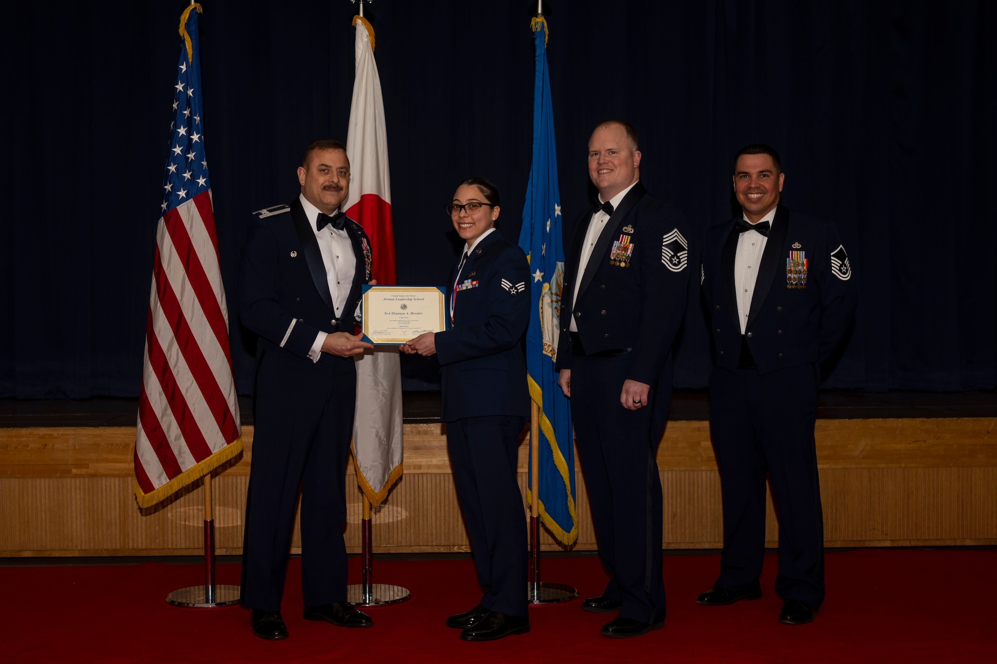 Group of military members in uniform pose for a photo holding a certificate.