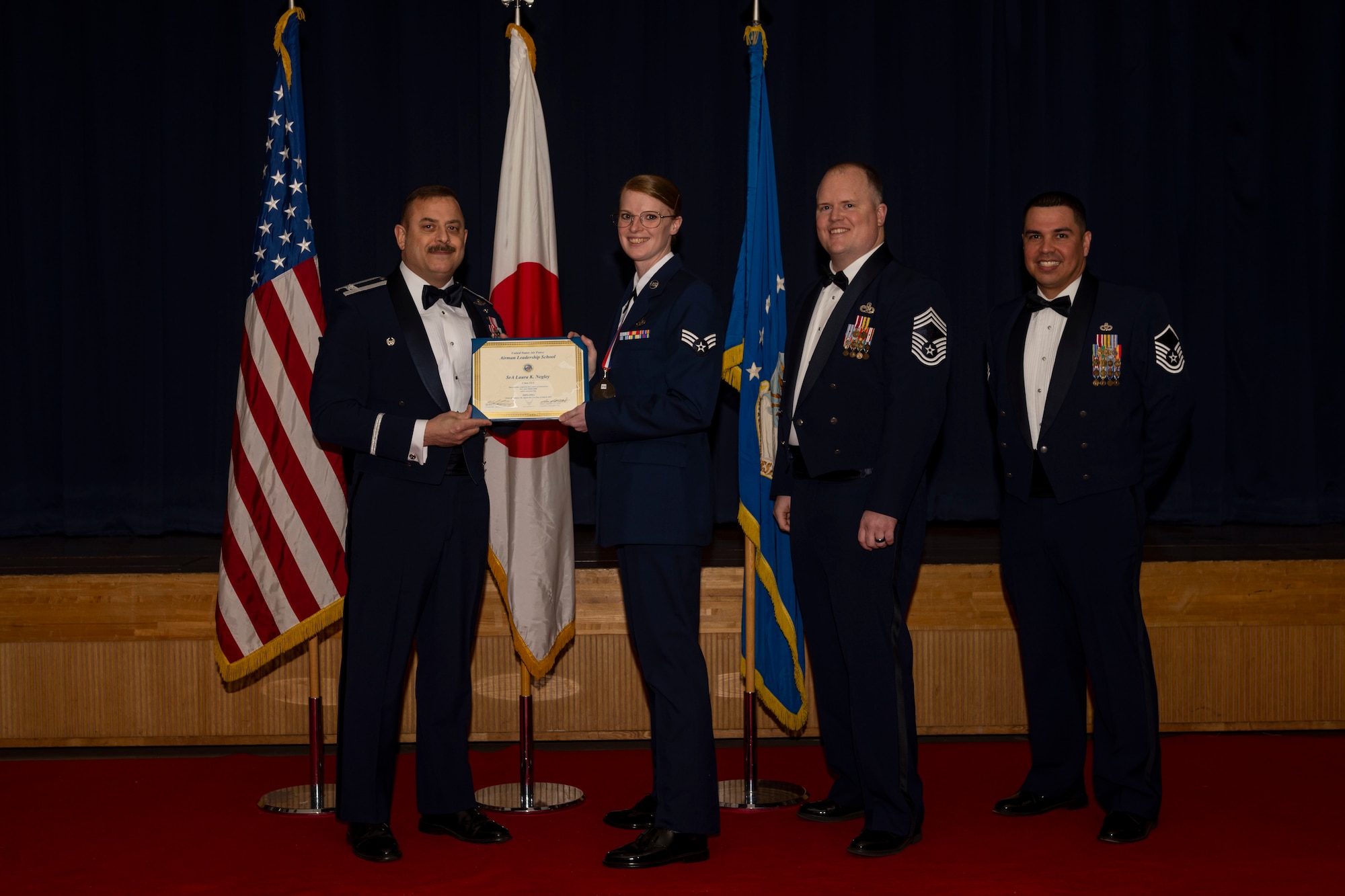 Group of military members in uniform pose for a photo holding a certificate.
