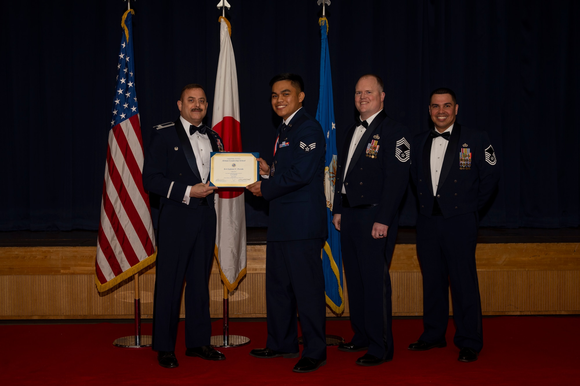 Group of military members in uniform pose for a photo holding a certificate.