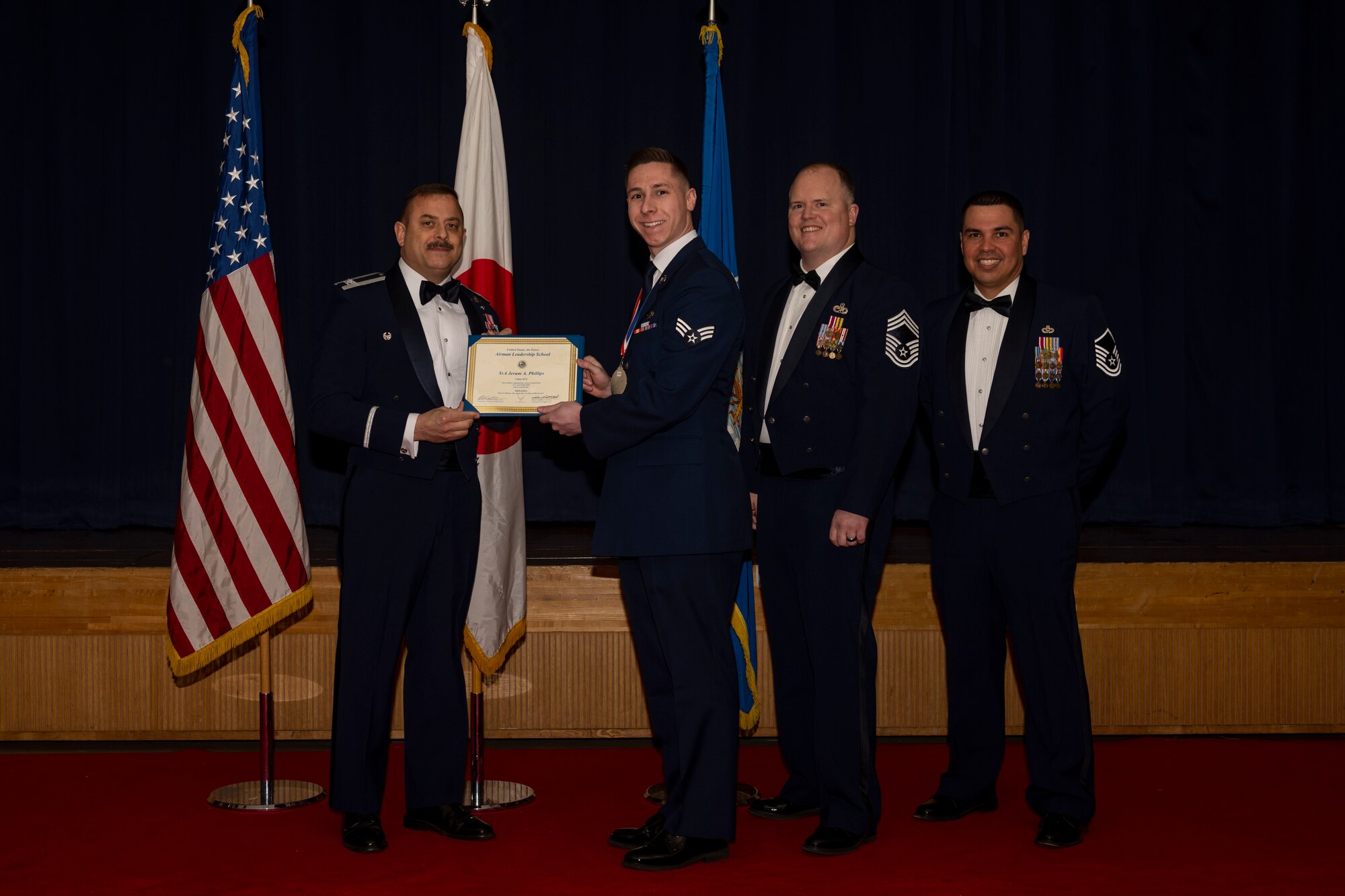 Group of military members in uniform pose for a photo holding a certificate.