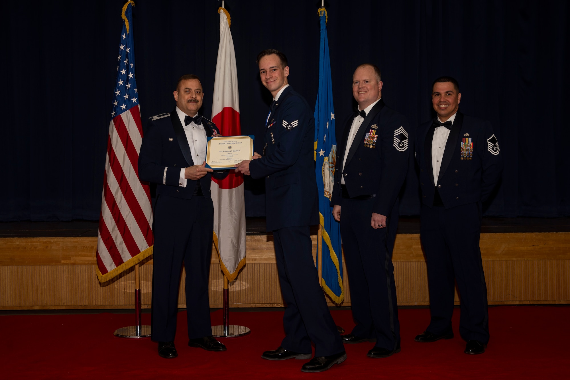 Group of military members in uniform pose for a photo holding a certificate.