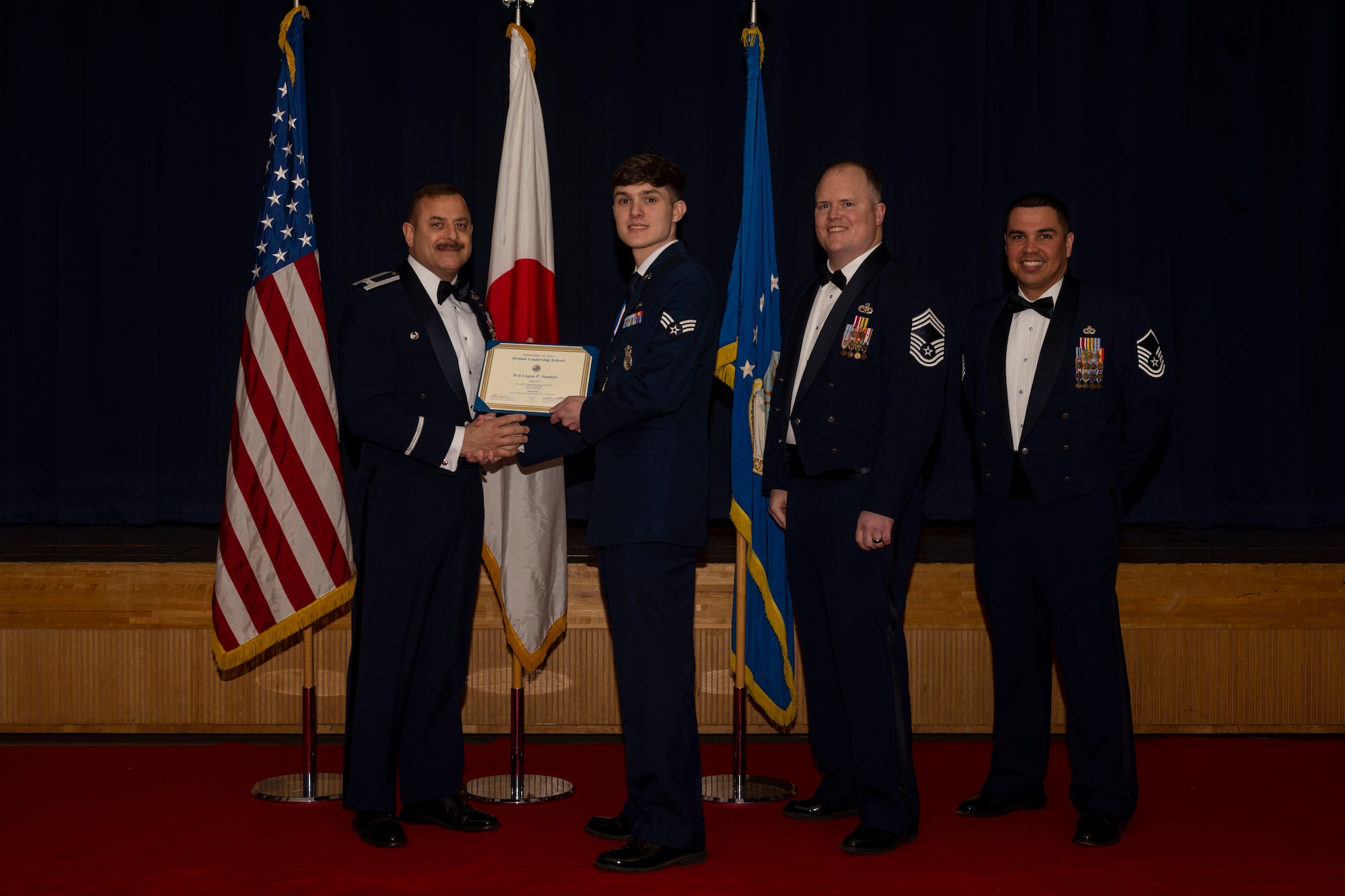 Group of military members in uniform pose for a photo holding a certificate.