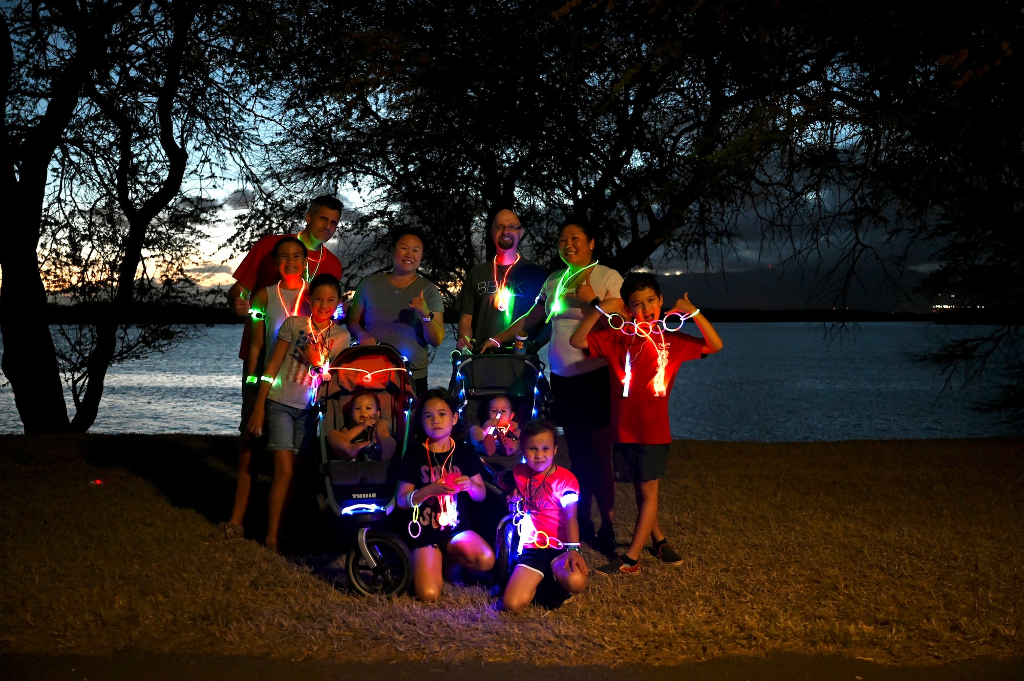 A family shows off their glow run gear after completing the Sexual Assault Awareness and Prevention Month glow run at Joint Base Pearl Harbor-Hickam, Hawaii, April 1, 2022. The 15th Wing Sexual Assault Prevention and Response Office hosted a glow run 5k to raise awareness about the resources their office provides and sexual assault in the military. (U.S. Air Force photo by 1st Lt. Benjamin Aronson)