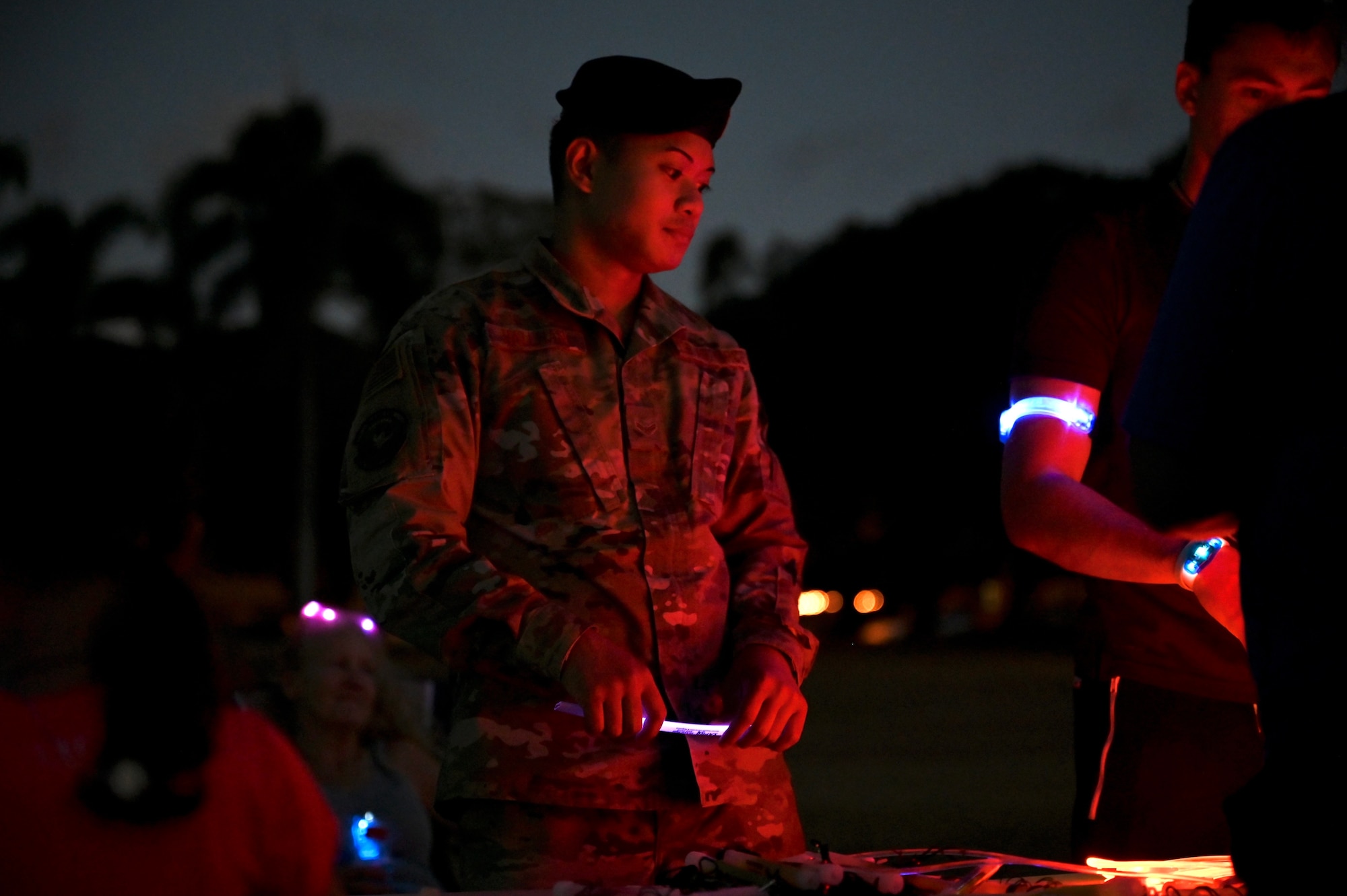 Airman First Class Francis Hallnan, 647th Security Forces Squadron installation entry controller, hands out glow sticks and bracelets to Airmen and their families at the Sexual Assault Awareness and Prevention Month glow run at Joint Base Pearl Harbor-Hickam, Hawaii, April 1, 2022. The theme of SAAPM this year is a call to action for individuals at all levels of the Department of Defense to use their personal strength to advance positive change in preventing sexual violence. (U.S. Air Force photo by 1st Lt. Benjamin Aronson)