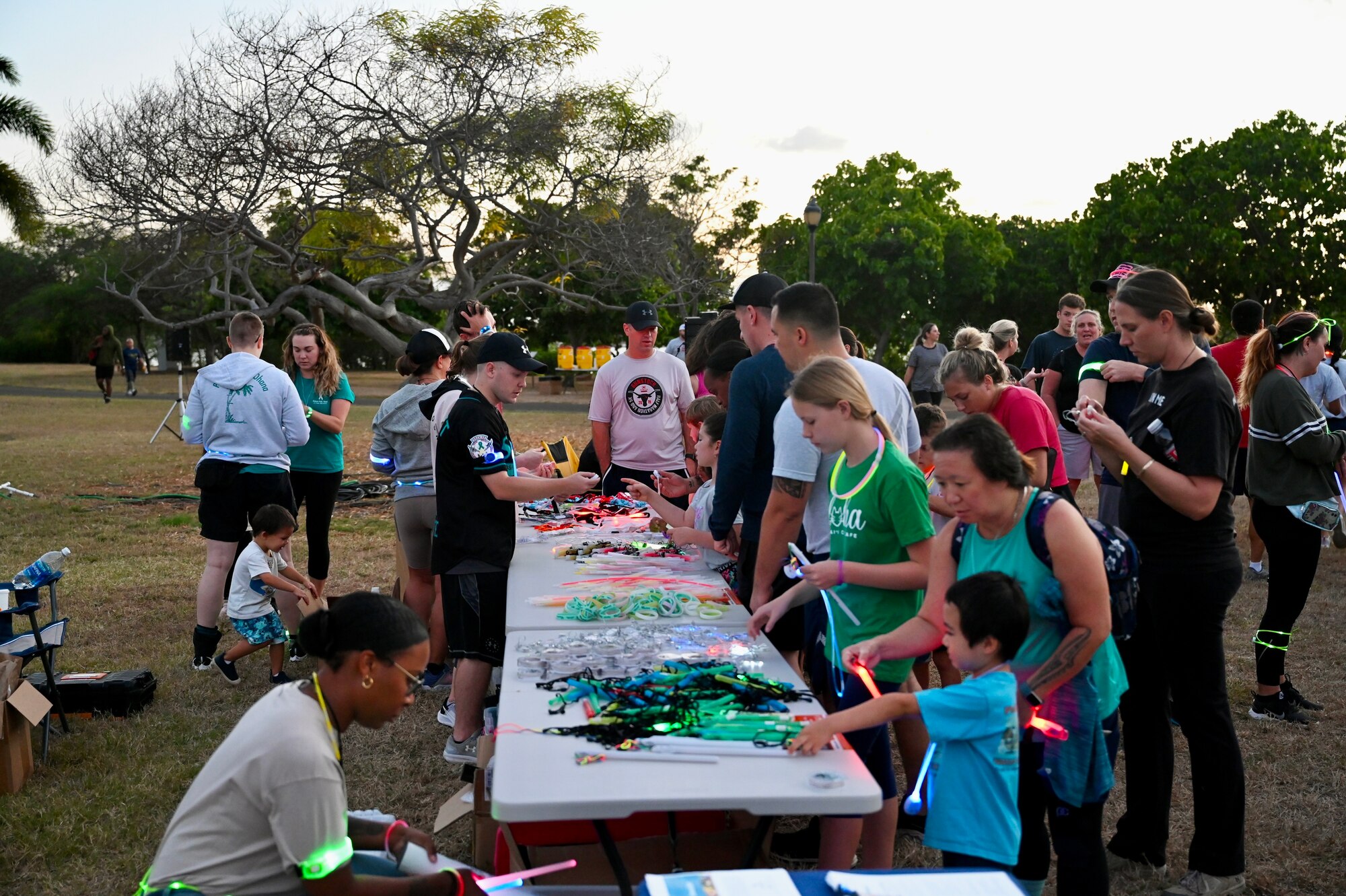 Volunteers hand out glow sticks and bracelets to Airmen and their families at the Sexual Assault Awareness and Prevention Month glow run at Joint Base Pearl Harbor-Hickam, Hawaii, April 1, 2022. The theme of SAAPM this year is a call to action for individuals at all levels of the Department of Defense to use their personal strength to advance positive change in preventing sexual violence. (U.S. Air Force photo by 1st Lt. Benjamin Aronson)