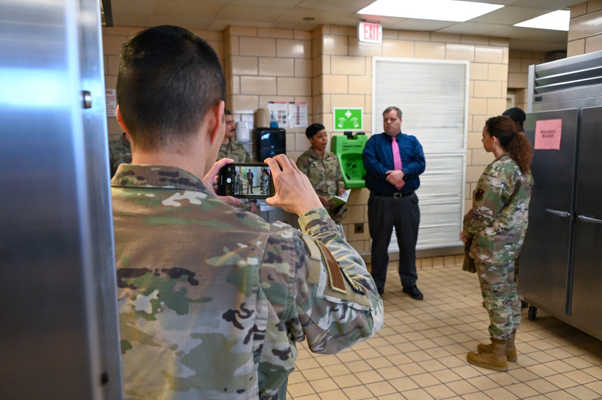 U.S. Air Force Maj. Timothy Truong, 97th Logistics Readiness Squadron deputy officer, takes a photo of Chief Master Sgt. Kristina Rogers, 19th Air Force command chief, talking with Airmen at Altus Air Force Base (AAFB), Oklahoma, March 31, 2022. Rogers toured the recently renovated dining facility at AAFB after viewing the newly built dorms. (U.S. Air Force photo by Senior Airman Kayla Christenson)