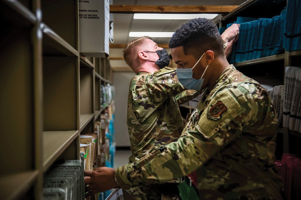Staff Sgt. Ramello Rhodes (front) and Senior Airman Ryan Faris, both assigned to the 445th Aeromedical Staging Squadron, sort through patient records at Naval Medical Center San Diego March 16, 2022.