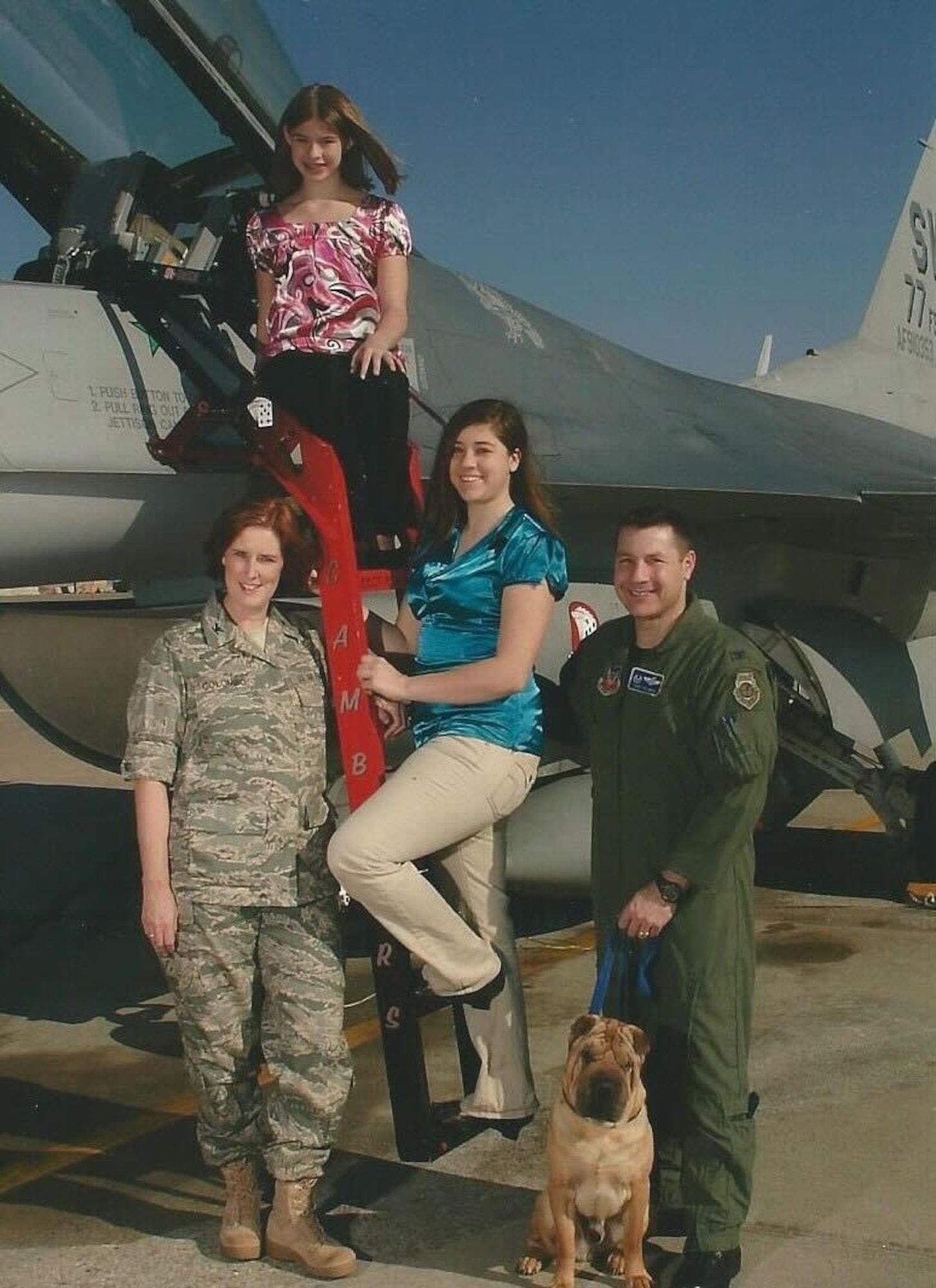 A family poses in front of a jet.