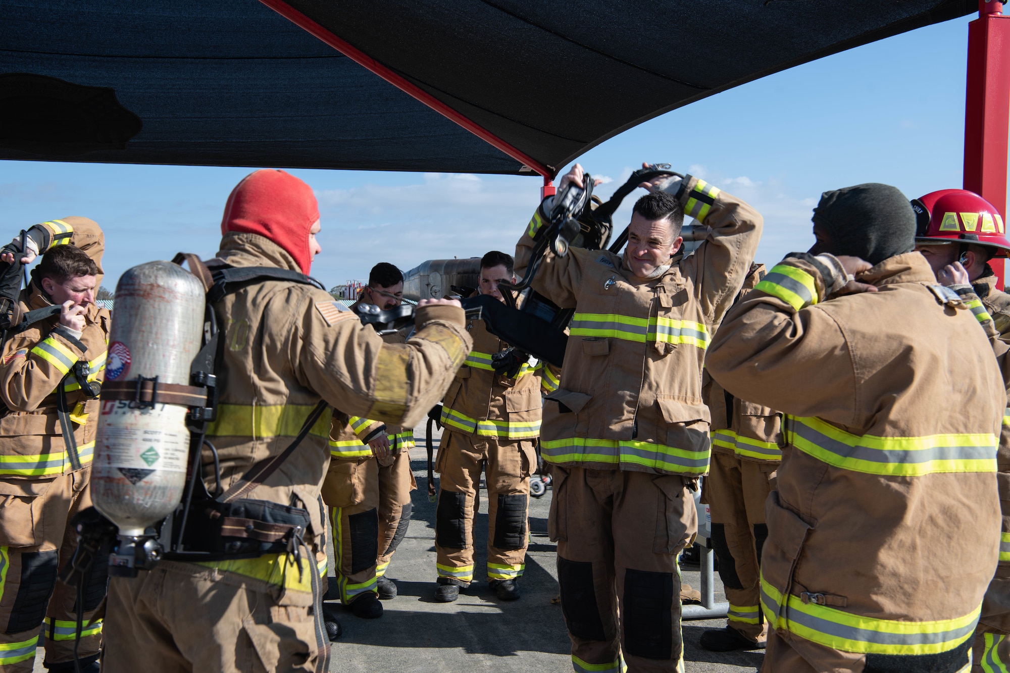 A group of firefighters don fire-protective gear.