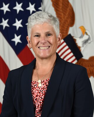 A woman smiles in front of a background of flags.
