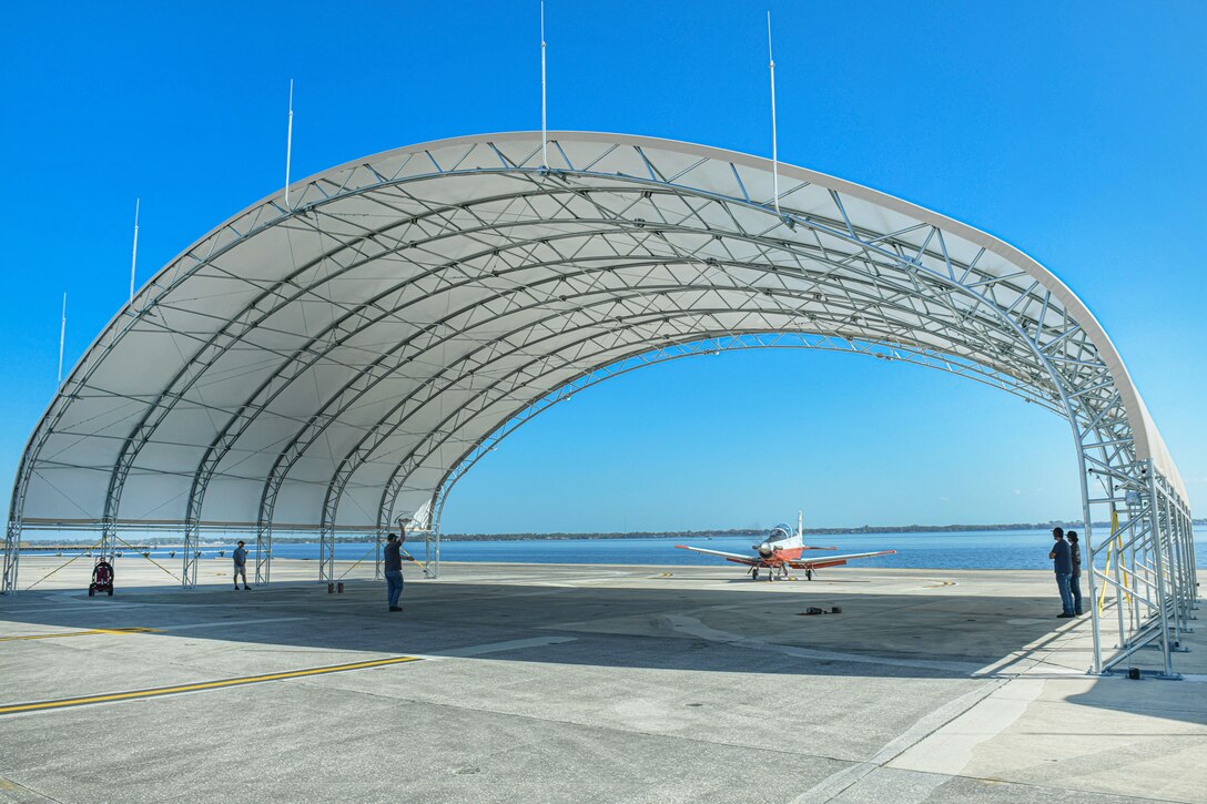A Fleet Readiness Center Southeast (FRCSE) ground crew recovers a Navy T-6A under an Environmental Protection Shelter. The shelters are the first aboard Naval Air Station Jacksonville and are built to withstand 135 mph winds. The shelters are the first aboard Naval Air Station Jacksonville and are built to withstand 135 mph winds. The huts are designed to protect aircraft and personnel from the harsh Florida weather.