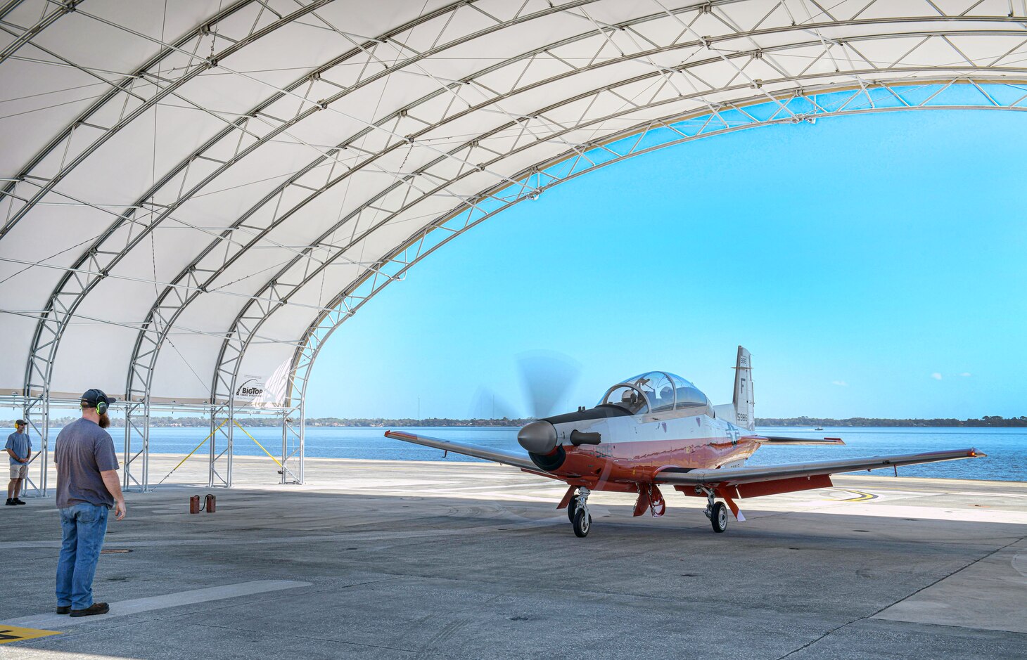 A Fleet Readiness Center Southeast (FRCSE) ground crew recovers a Navy T-6A under an Environmental Protection Shelter. The shelters are the first aboard Naval Air Station Jacksonville and were designed to withstand 135 mph winds and protect aircraft and personnel from the harsh Florida weather.