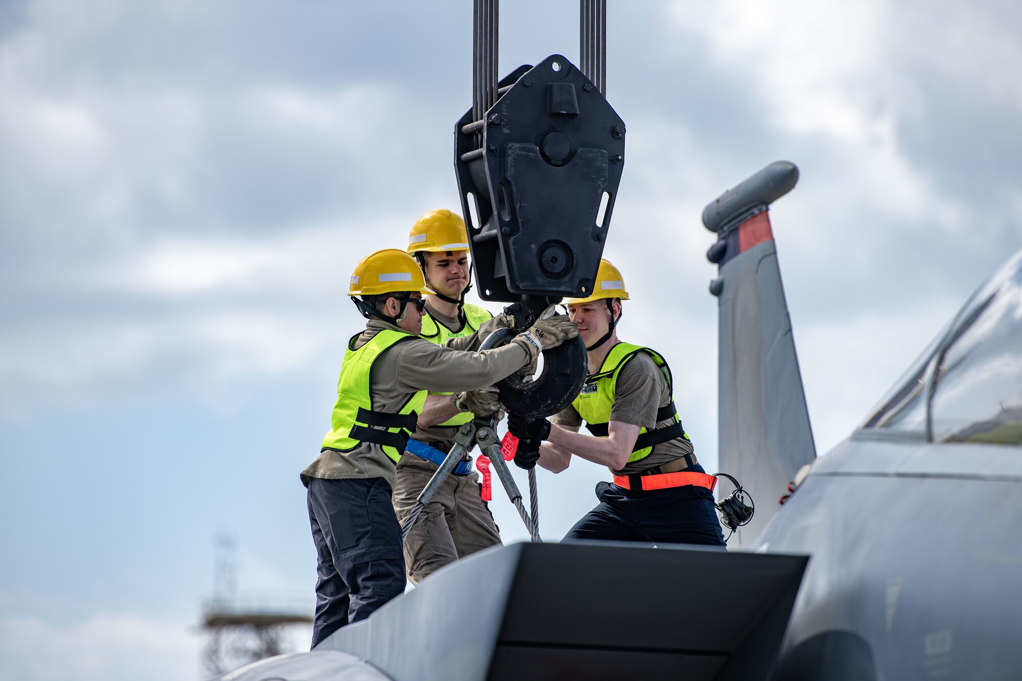 Airmen connect a hook to a plane.