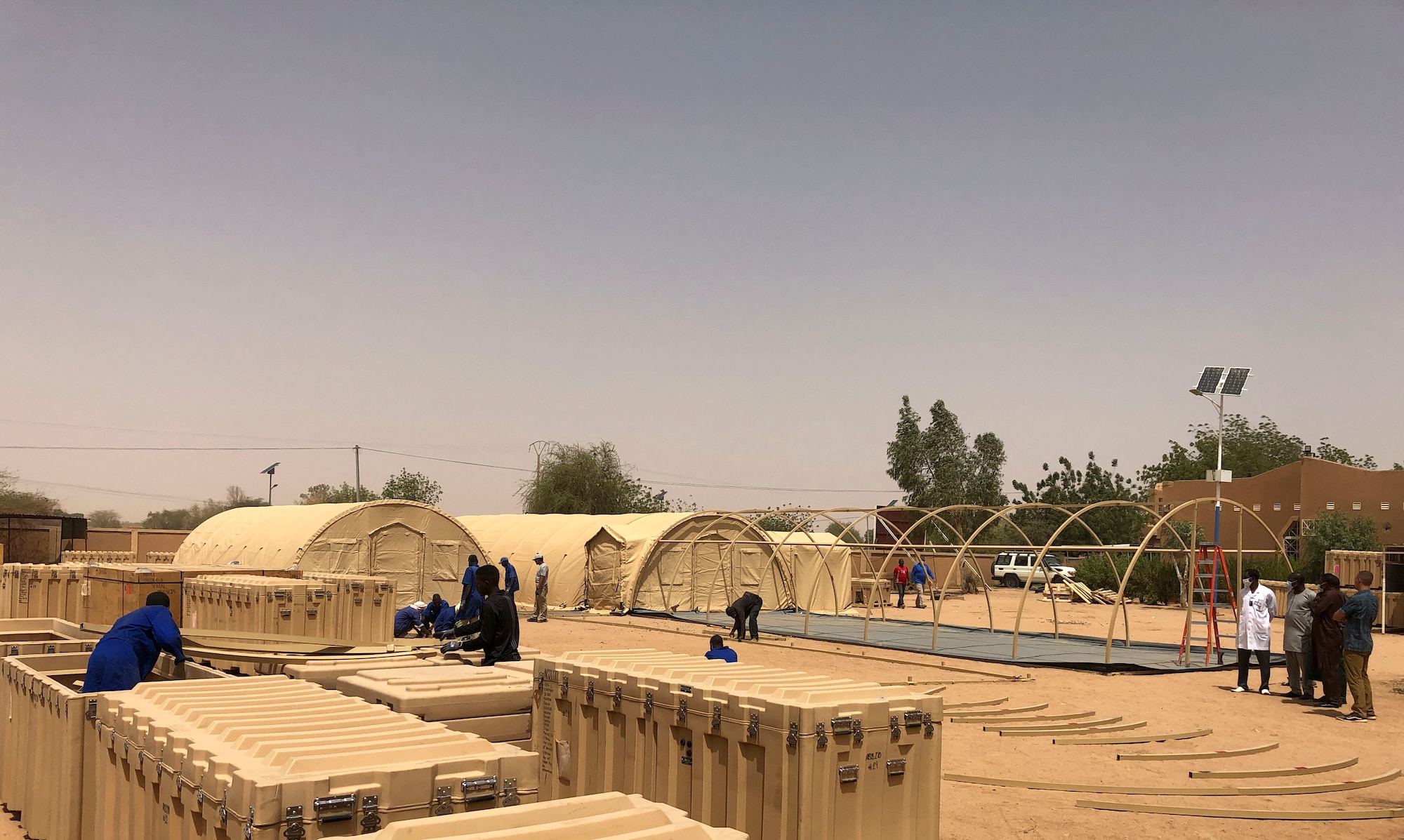 Nigerien workers build a mobile field hospital financed by the U.S. Africa Command through the Overseas Humanitarian, Disaster Assistance, and Civic Aid program in Agadez, Niger, March 22, 2022. U.S. subject matter experts taught Nigerien workers how to construct, maintain, de-construct, and move the mobile hospital. The $1.6 million, 4,592 square-foot mobile field hospital increases Agadez Regional Hospital’s capacity by an additional 30 beds, complete with the medical tools and resources to care for the 670,000-person community and surrounding areas. (U.S. Army courtesy photo by Staff Sgt. Peter Maenner)