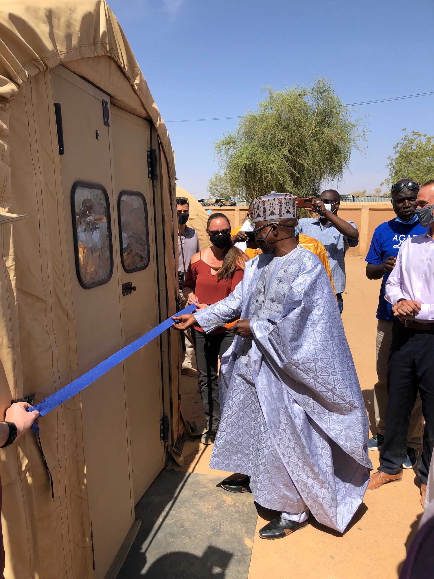 Mr. Magagi Maman Dada, Agadez Regional Governor, cuts a ceremonial ribbon in front of the newly built/donated mobile field hospital in Agadez, Niger, April 4, 2022. The $1.6 million, 4,592 square-foot mobile field hospital financed by the U.S. Africa Command through the Overseas Humanitarian, Disaster Assistance, and Civic Aid program increases Agadez Regional Hospital’s capacity by an additional 30 beds, complete with the medical tools and resources to care for the 670,000-person community and surrounding areas. (U.S. Air Force courtesy photo by Capt. Keith Richards)
